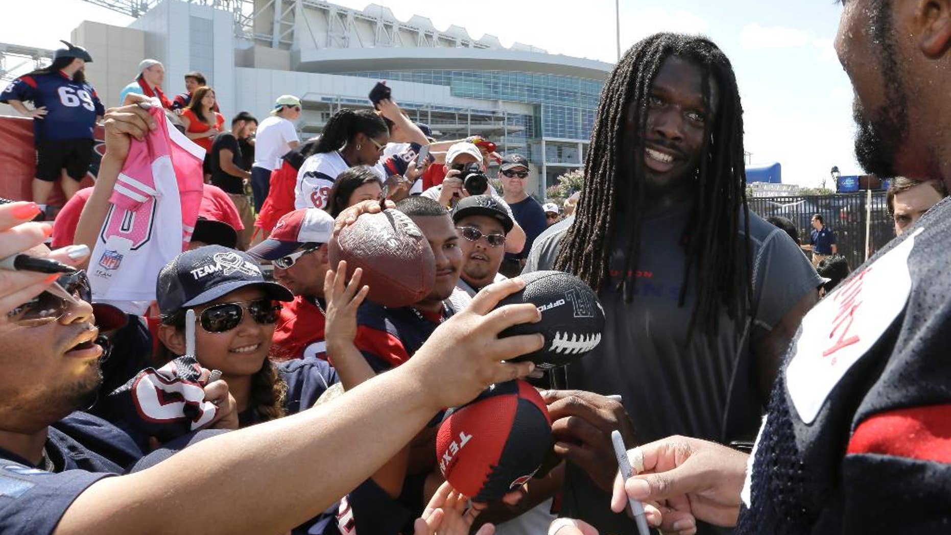 Houston Texans' Jadeveon Clowney, second from right, talks with teammate Duane Brown, right, as they sign autographs for fans after an NFL football training camp practice Sunday, July 27, 2014, in Houston. (AP Photo/David J. Phillip)