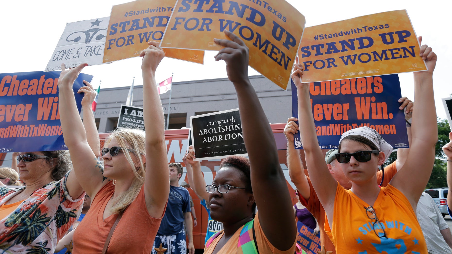File - In this July 9, 2013 file photo, opponents and supporters of an abortion bill hold signs near a news conference outside the Texas Capitol, in Austin, Texas. New abortion restrictions passed by the Texas Legislature are unconstitutional and will not take effect as scheduled on Tuesday, a federal judge has ruled. (AP Photo/Eric Gay, File)