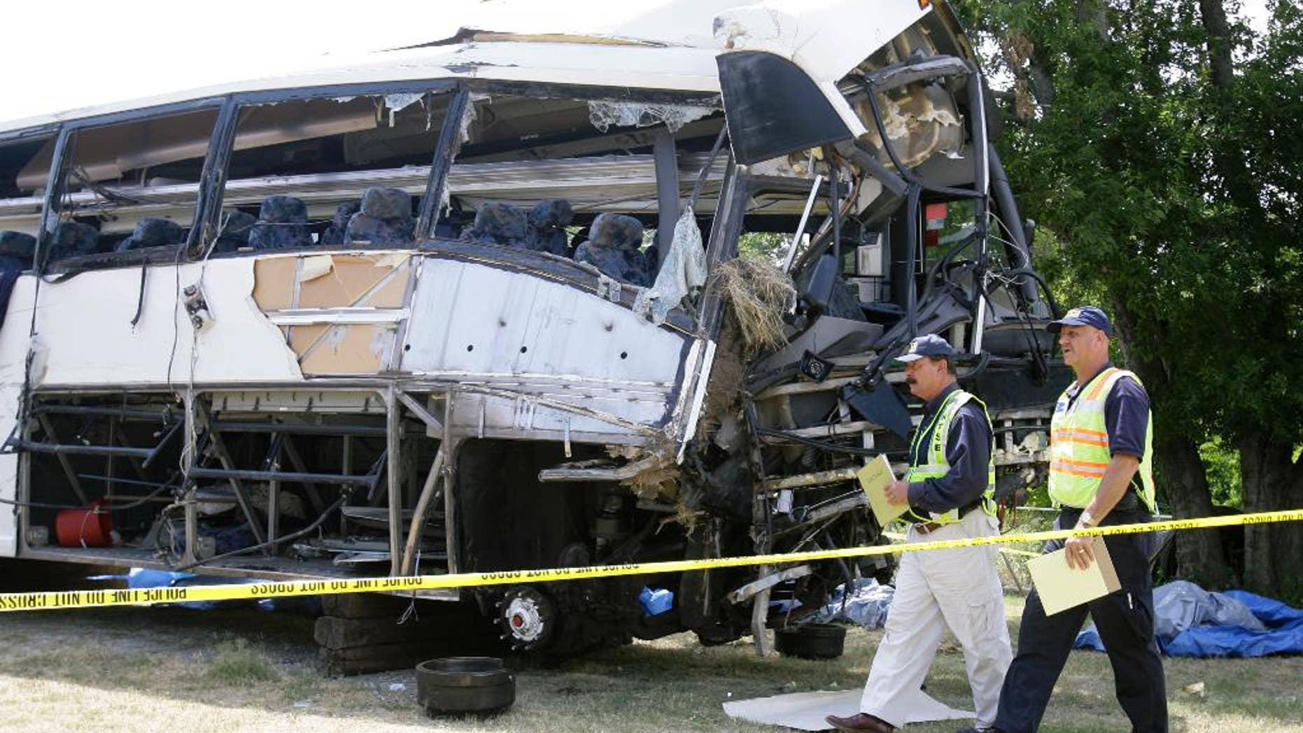 FILE - National Transportation Safety Board investigators David Rayburn, left, and Robert Accetta walk in this Aug. 10, 2008 file photo past a charter bus involved in a deadly accident early Friday that killed 17 people and left at least eight others in critical condition in Sherman, Texas. The owner of the Houston bus company who was charged after a 2008 crash has avoided prison after a federal judge sentenced him to three years of probation in a plea agreement Friday Oct. 24, 2014. (AP Photo/Matt Slocum, File)