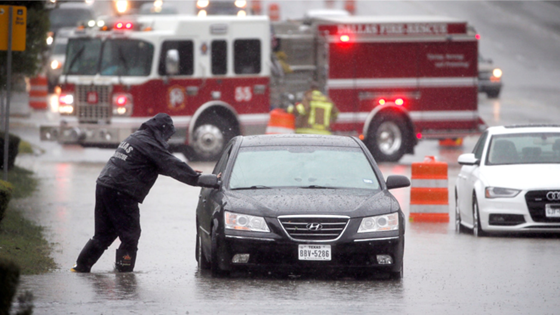A Dalls Fire Rescue responder makes his way over to a stalled vehicle to check on the driver still inside on Friday, Oct. 23, 2015, in Dallas. The vehicle stalled after the road quickly flooded during a heavy rain fall. (AP Photo/Tony Gutierrez)