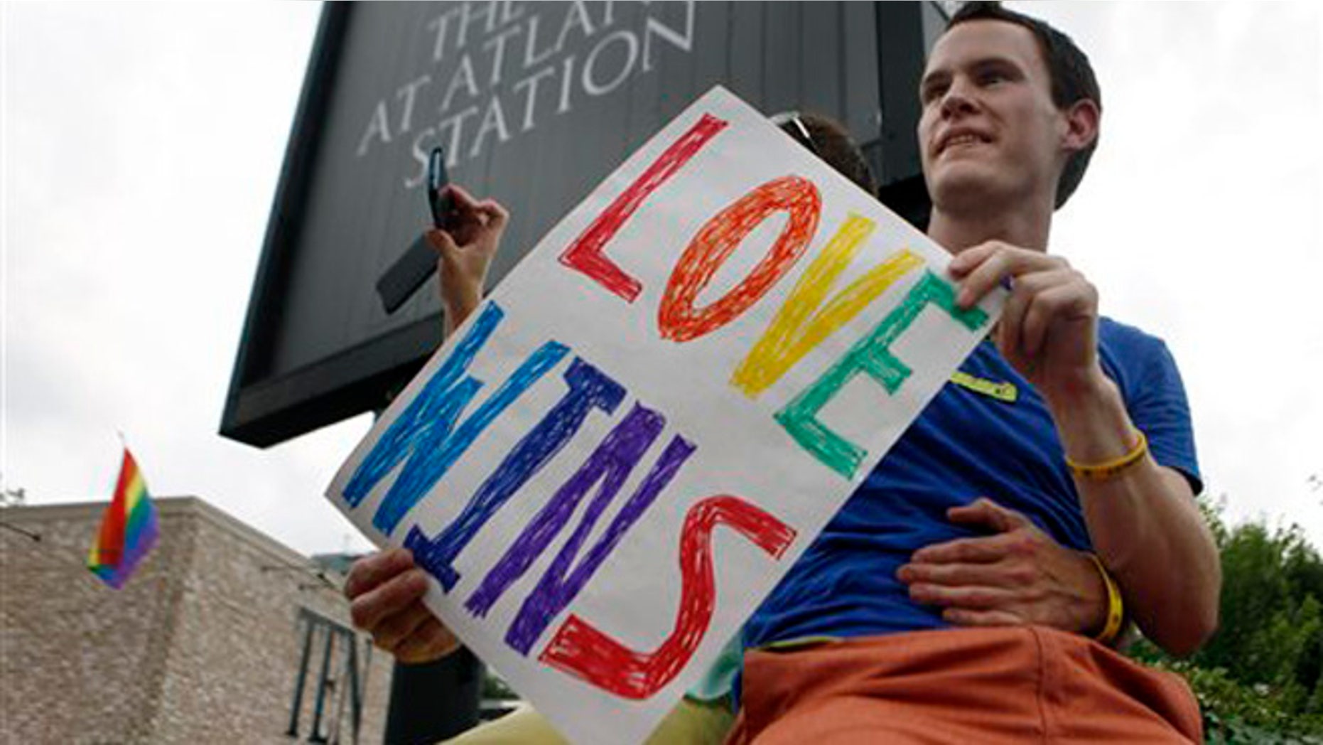 FILE - Int his June 26, 2013 file photo, Daniel Hicks sits on a pillar with his boyfriend to watch the local crowd celebrate the U.S. Supreme Court's rulings on two landmark gay rights cases surrounding same-sex marriage, in Atlanta. Less than two weeks after a federal judge declared Virginiaâs ban on same-sex marriage unconstitutional, a new effort has been launched in the South seeking to build wider acceptance of gay and lesbian couples in the hope of overturning similar bans across the region. (AP Photo/Jaime Henry-White, File)