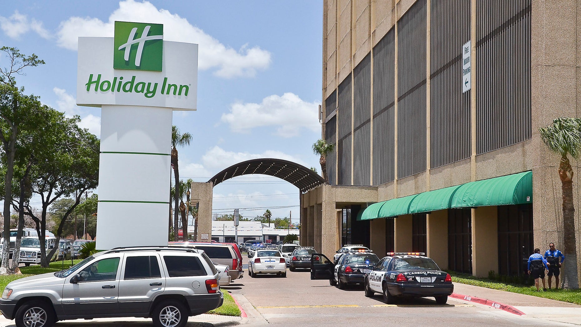 June 19, 2012: A line of Laredo Police Department vehicles line the entrance to the Holiday Inn Civic Center in Laredo, Texas, where two young boys were shot.