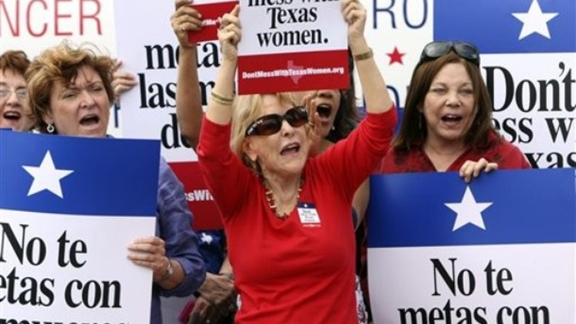 March 6, 2012: Mary Green, Peg Armstrong and Jan Perrault hold up signs during Women's Health Express, a bus event held in San Antonio, Texas, to protest the attempt to cut Planned Parenthood out of the state's Women's Health Plan.