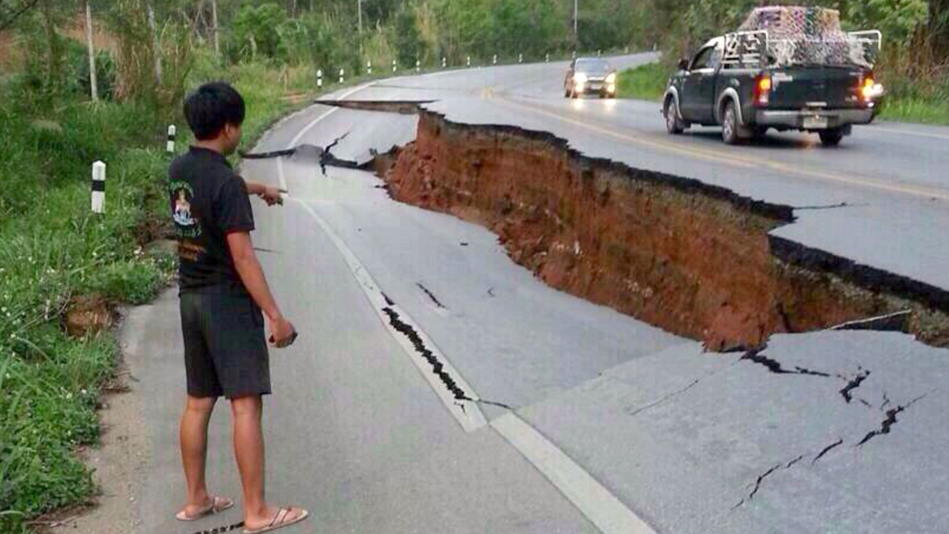May 5, 2014 - A man eyes a big crack on a damaged road following a strong earthquake in Phan district of Chiang Rai province, northern Thailand. The strong quake shook northern Thailand and Myanmar Monday evening, and light damage was reported.