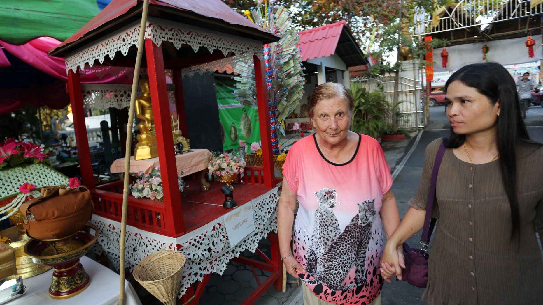 Margrit, left, an Alzheimer patient from Switzerland, walks with a Thai caretaker during a tour at a Buddhist temple in Chiang Mai province, northern Thailand. (AP Photo/Apichart Weerawong)