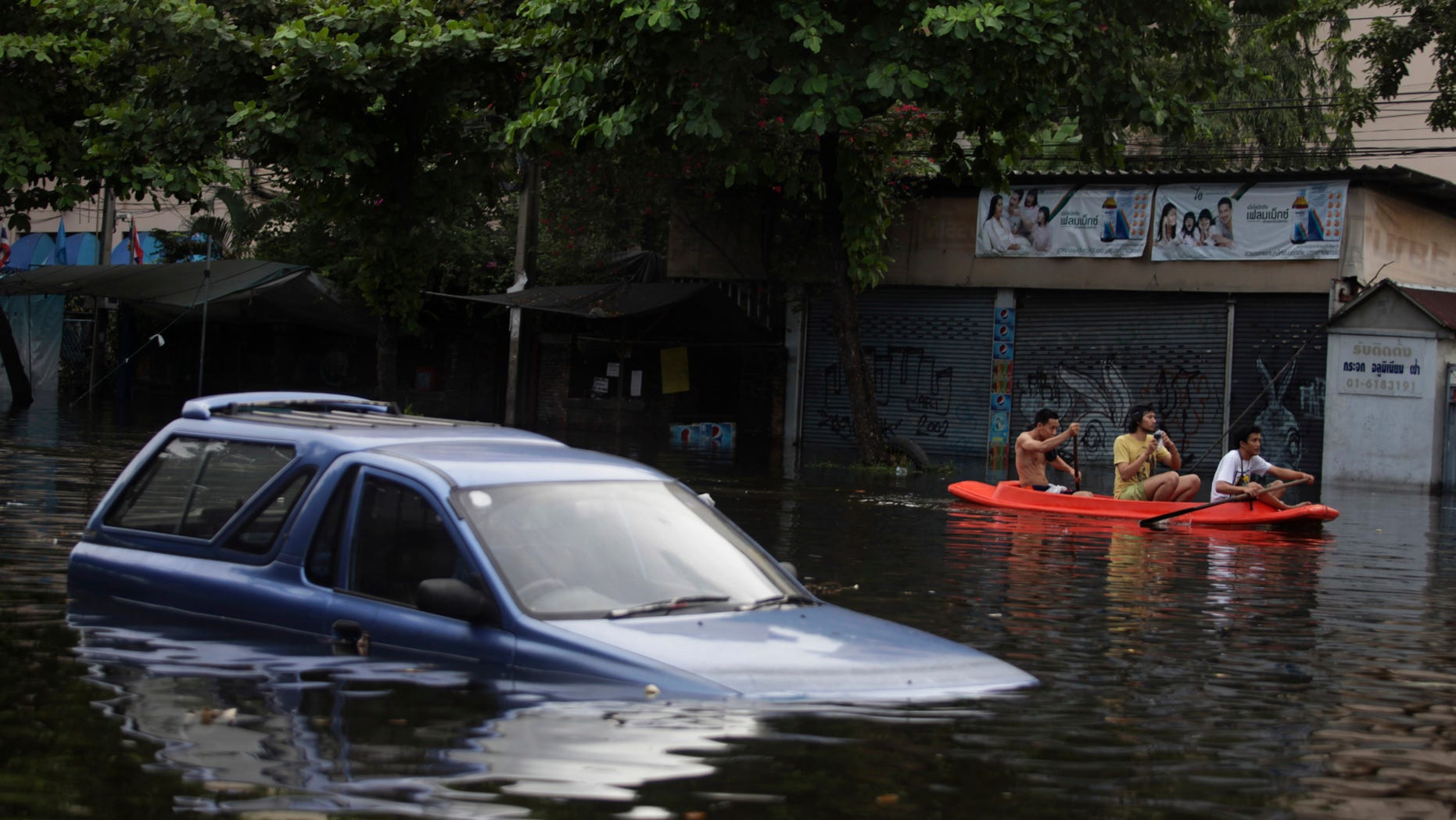 Oct. 28, 2011: Thai men row their boat past a vehicle submerged in floodwaters in Bangkok, Thailand.