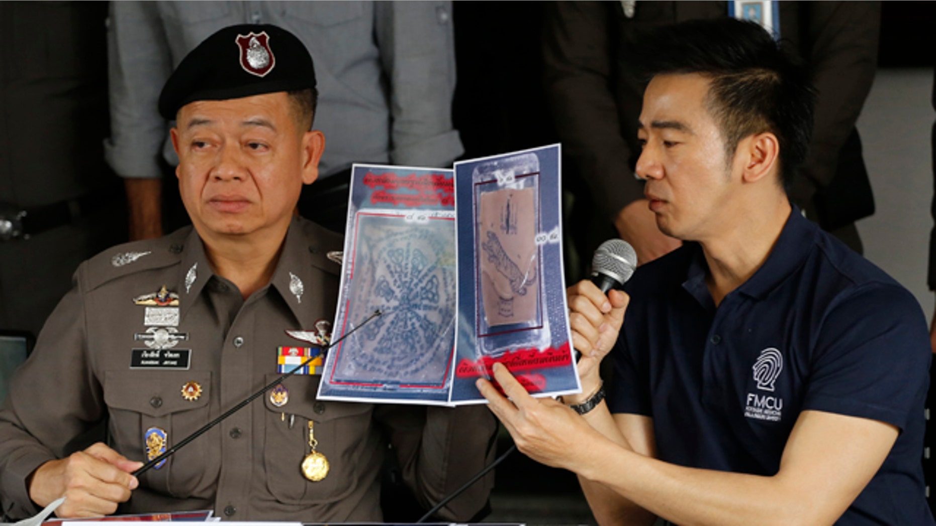 November 17, 2014: Thai police officers show pictures of a tattooed human skin during a press conference at Bangpongpang police station in Bangkok. (AP Photo/Sakchai Lalit)