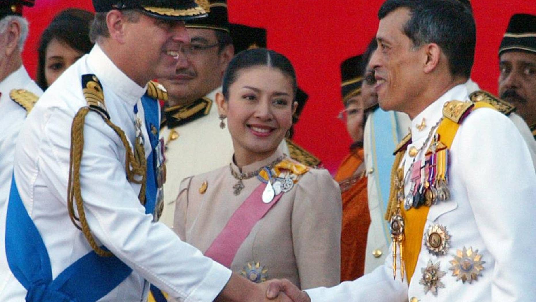 FILE - In this Aug. 31, 2007 file photo, Thailand's Crown Prince Maha Vajiralongkorn, right, accompanied by his royal consort Princess Srirasm, center, shakes hands with Britain's Prince Andrew during a parade at the Merdeka Square in Kuala Lumpur, marking Malaysia's 50 years of independence from Britain. The woman who was in line to become Thailand's next queen has relinquished her royal title following revelations last month that several members of her family were detained in a high-profile corruption scandal. A brief statement from the palace's Royal Gazette that was made public late Friday, Dec. 12, 2014 said Srirasm had asked permission to give up her royal status. (AP Photo/Lai Seng Sin, File)