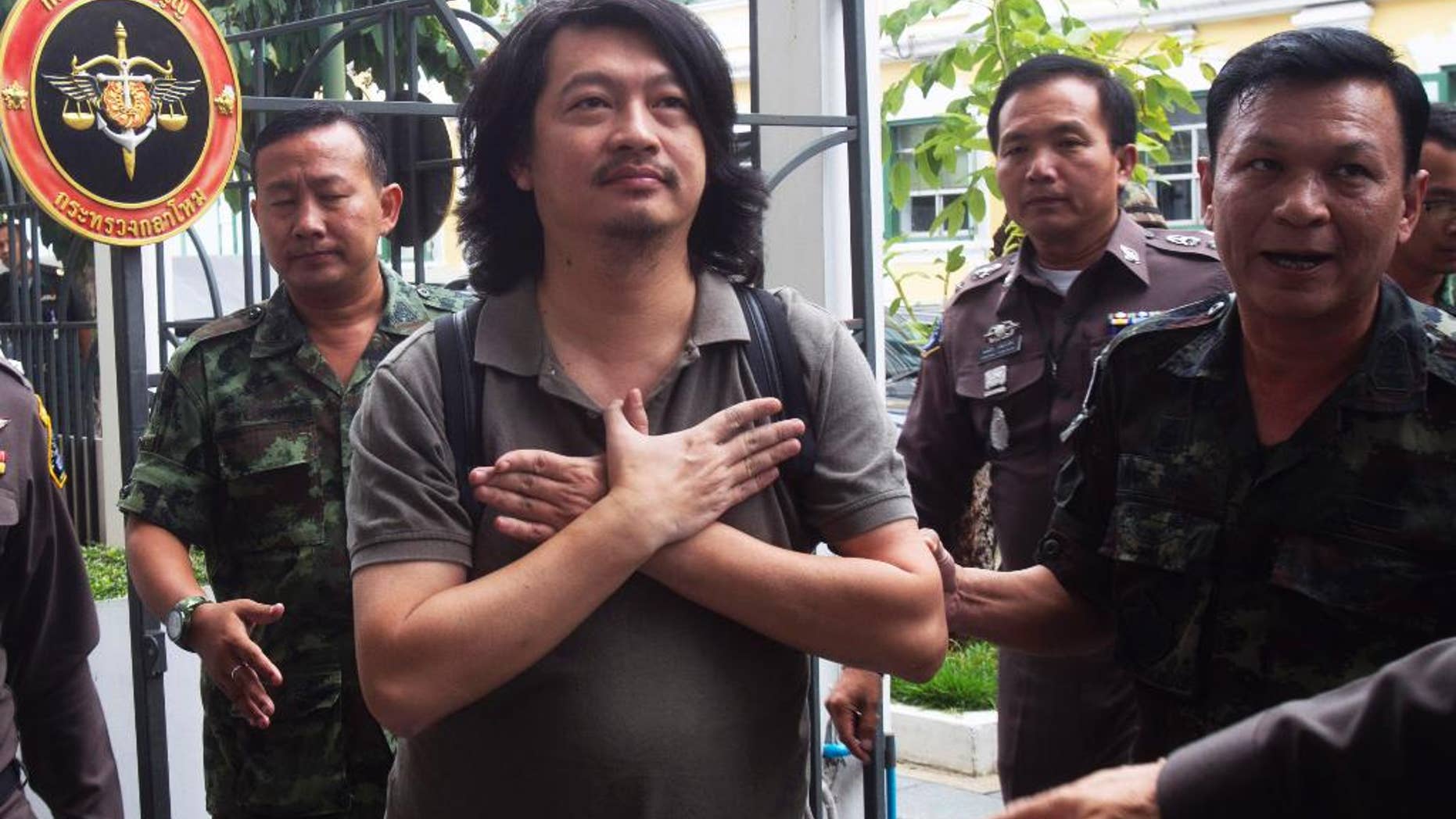 FILE - In this Thursday, June 12, 2014 file photo, Sombat Boonngam-anong gestures a sign of freedom while arriving at the military court in Bangkok, Thailand. Sombat was released from police custody Tuesday, July 1, 2014, on conditions that he not incite unrest or travel overseas without permission from authorities after posting a 300,000 baht ($9,250) bail, said Police Col. Kittirat Noiponthong. (AP Photo/Sakchai Lalit, File)