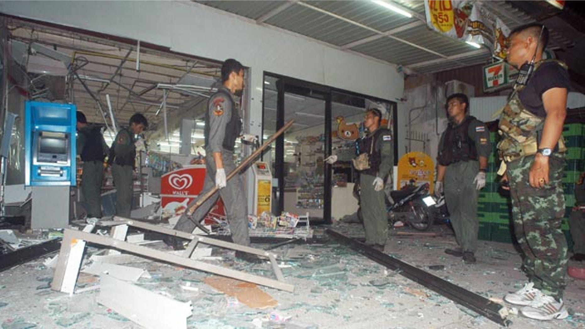 May 24, 2014: Thai police officers and soldiers examine the site where a bomb exploded at a super store in Pattani province, southern Thailand. (AP Photo/Sumeth Panpetch)