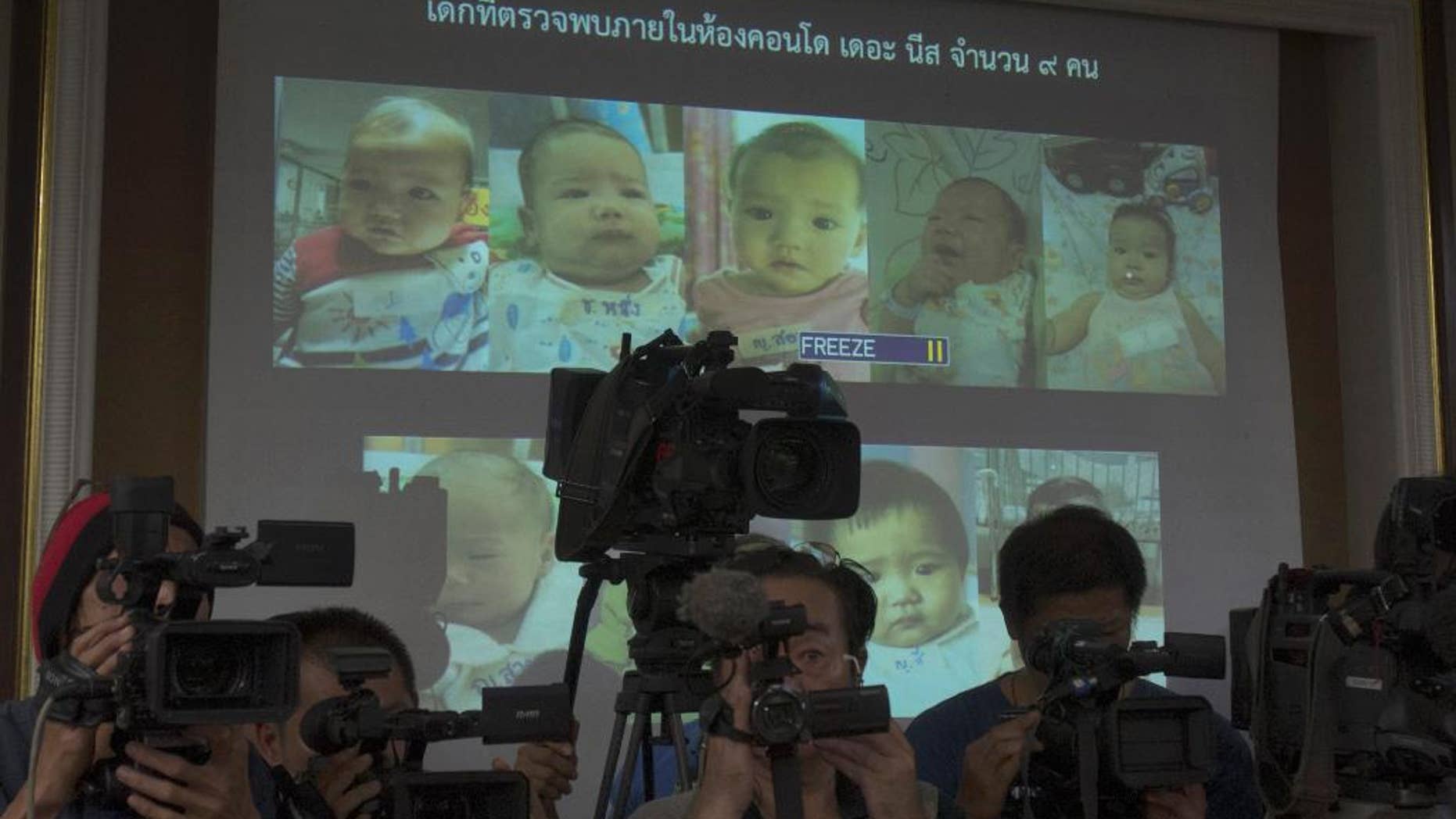 FILE - In this Tuesday, Aug. 12, 2014 file photo, Thai police display pictures of surrogate babies born to a Japanese man who is at the center of a surrogacy scandal during a press conference at the police headquarters in Chonburi, Thailand. A string of recent scandals has lifted a lid on Thailand's largely unregulated commercial surrogacy industry, which has been around for over a decade. (AP Photo/Sakchai Lalit)