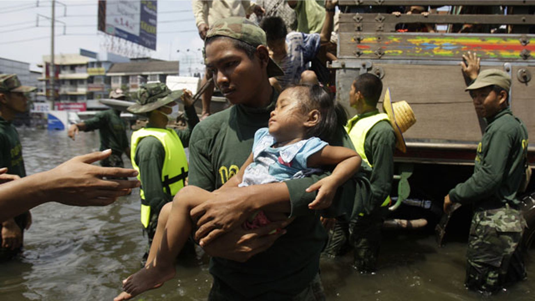 Oct. 21, 2011: A Thai soldier carries a girl down a truck as they evacuate to higher grounds at the flooded district of Rangsit on the outskirts of Bangkok, Thailand.
