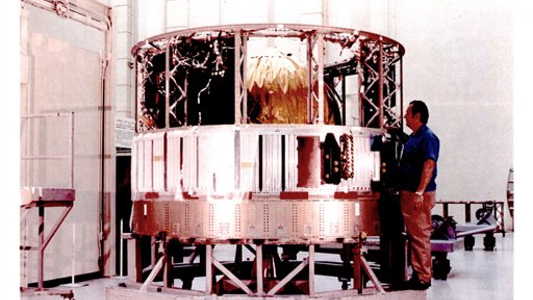 This undated image made available by the National Reconnaissance Office is a declassified image of a man standing next to a satellite control section from the Hexagon program.
