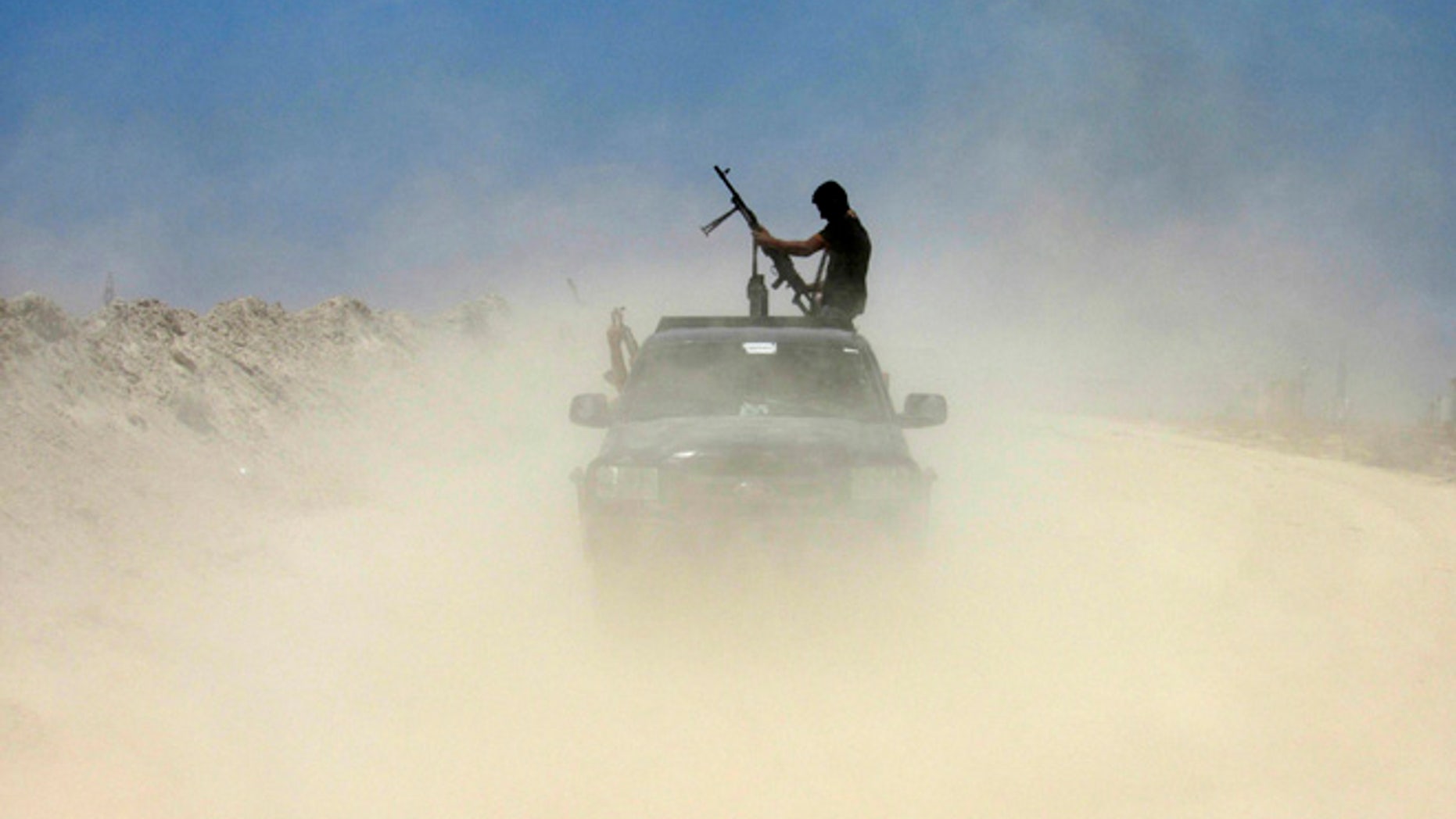 FILE - A fighter with Badr Brigades an armed Shiite group under the umbrella of the Popular Mobilization Forces loads his rifle as Iraqi security forces and allied Shiite Popular Mobilization Forces and Sunni tribal fighters, take combat positions outside Fallujah, 40 miles (65 kilometers) west of Baghdad, Iraq, Monday, May 23, 2016. Iraqi government forces on Monday pushed Islamic State militants out of some agricultural areas outside Fallujah as they launched a military offensive to recapture the city from the extremists, officials said. (AP Photo/Rwa Faisal)