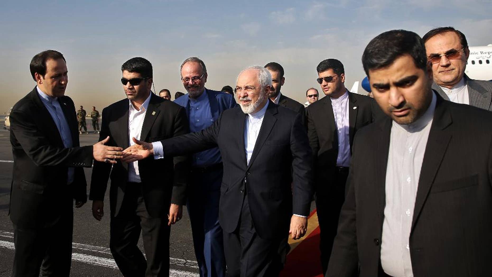 Iran's Foreign Minister Mohammad Javad Zarif, who is also Iran's top nuclear negotiator, center, shakes hands with an official upon arrival at the Mehrabad airport in Tehran, Iran, Wednesday, July 15, 2015. Zarif and his entourage returned to Tehran on Wednesday morning, a day after Iran and the West reached a historic nuclear deal. (AP Photo/Ebrahim Noroozi)