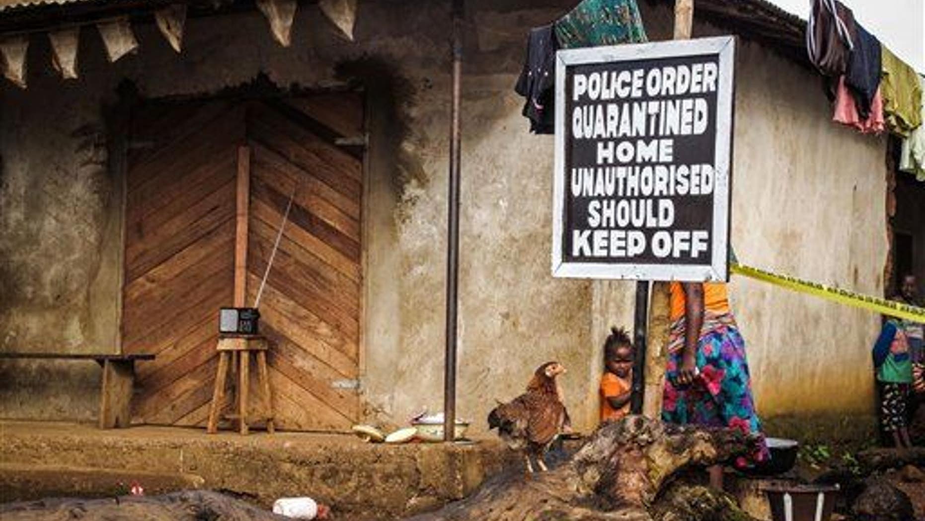 A child stands near a sign advising of a quarantined home in Port Loko, Sierra Leone.