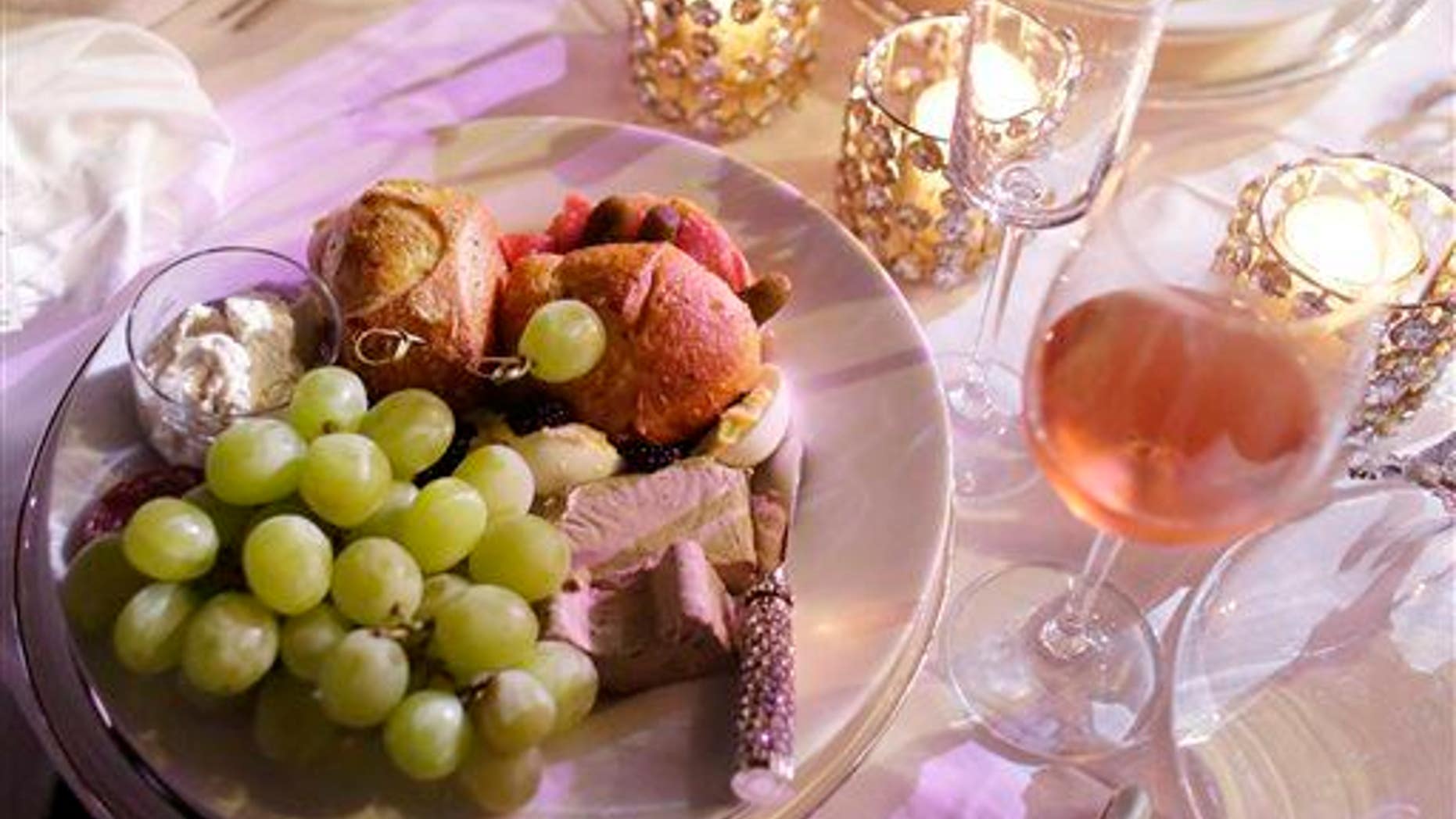 A plate of food is shown with candles and wine during the "Diner en Blanc" event at SoundScape Park, Tuesday, Dec. 9, 2014, in Miami Beach, Fla.