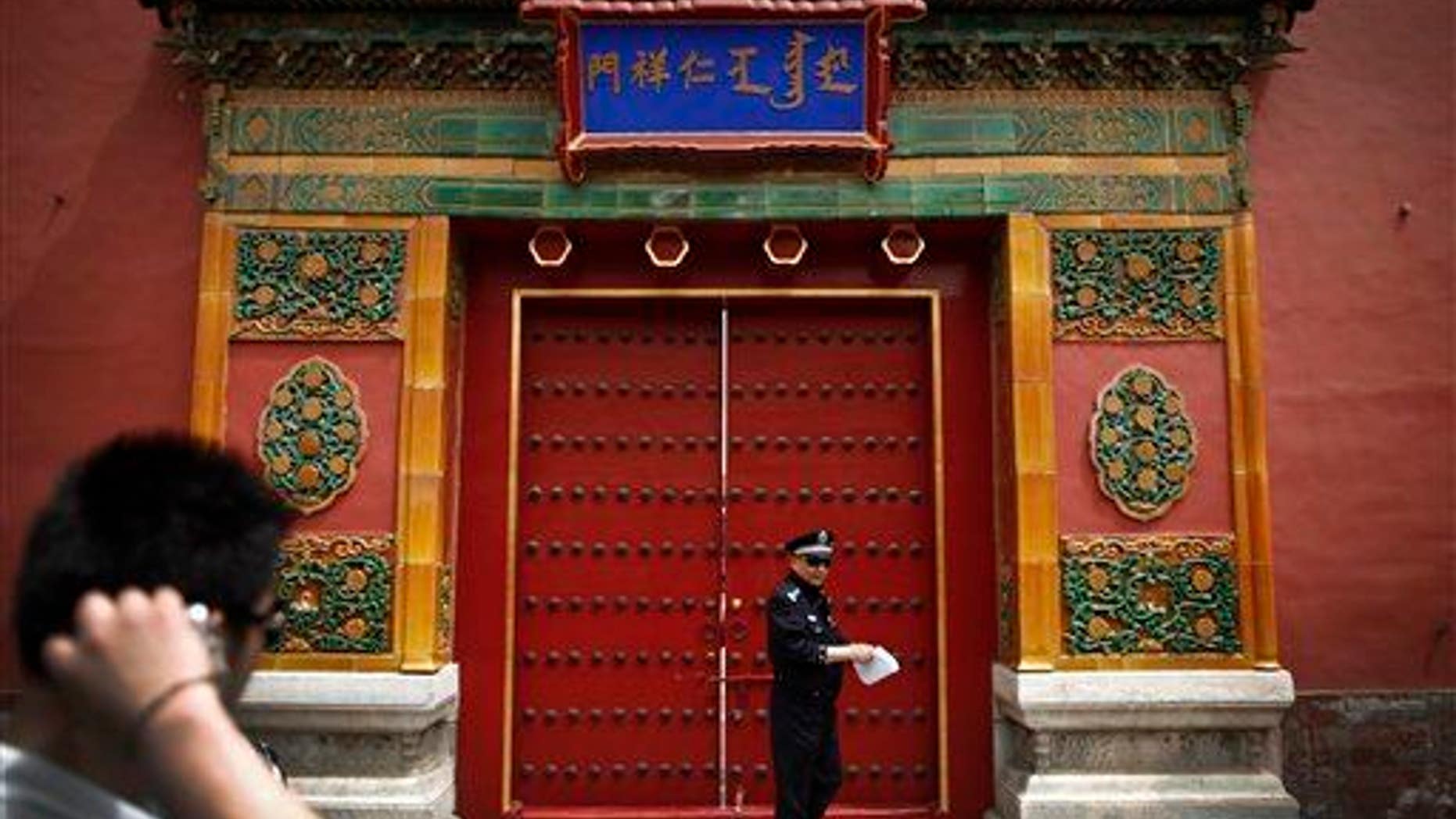 A tourist looks at a policeman stand in front of the entrance doorway to the Palace Museum, which announced the find.