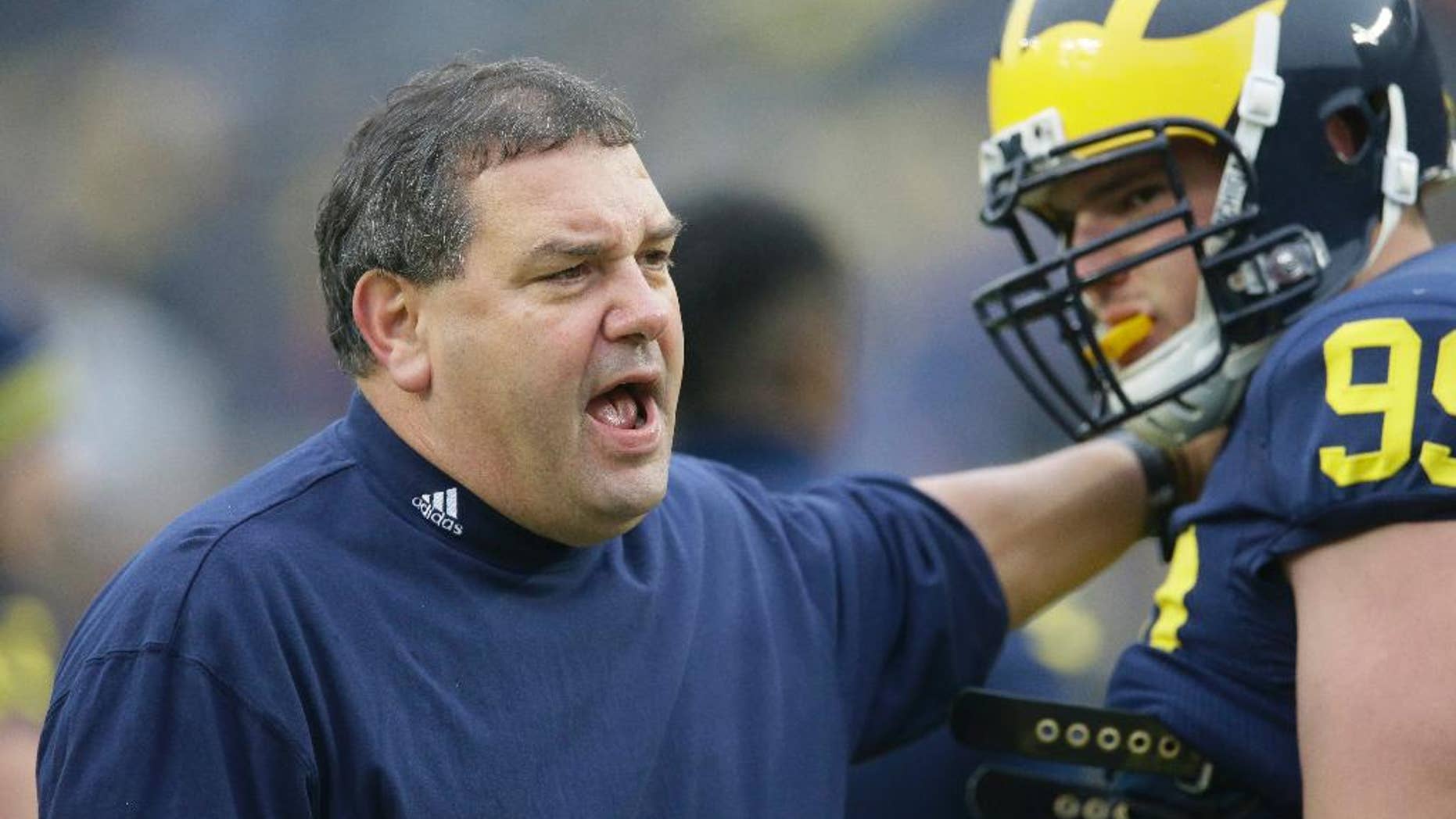 FILE - In this Nov. 22, 2014, file photo, Michigan head coach Brady Hoke, left, talks with defensive tackle Matthew Godin during warm ups before an NCAA college football game against Maryland in Ann Arbor, Mich. While keeping track on rivalries and games with playoff implication, there are a few coaching hot spots to keep an eye on this weekend. Another loss will put Michigan out of the postseason and make it three straight seasons of declining win totals under Hoke. (AP Photo/Carlos Osorio, File)