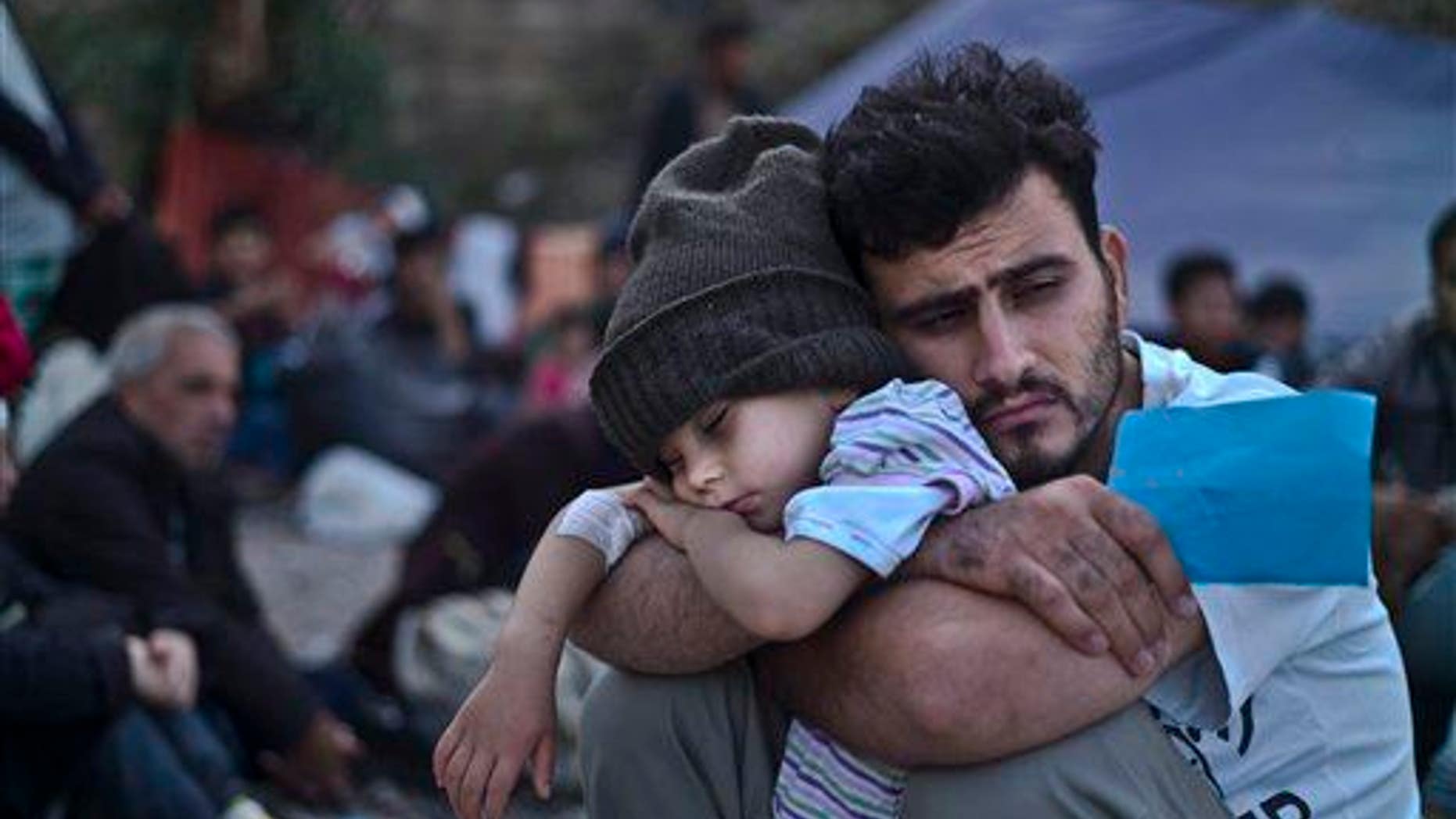 A Syrian refugee child sleeps on his father's arms while waiting at a resting point to board a bus, after arriving on a dinghy from the Turkish coast to the Greek island of Lesbos, Oct. 4 , 2015.
