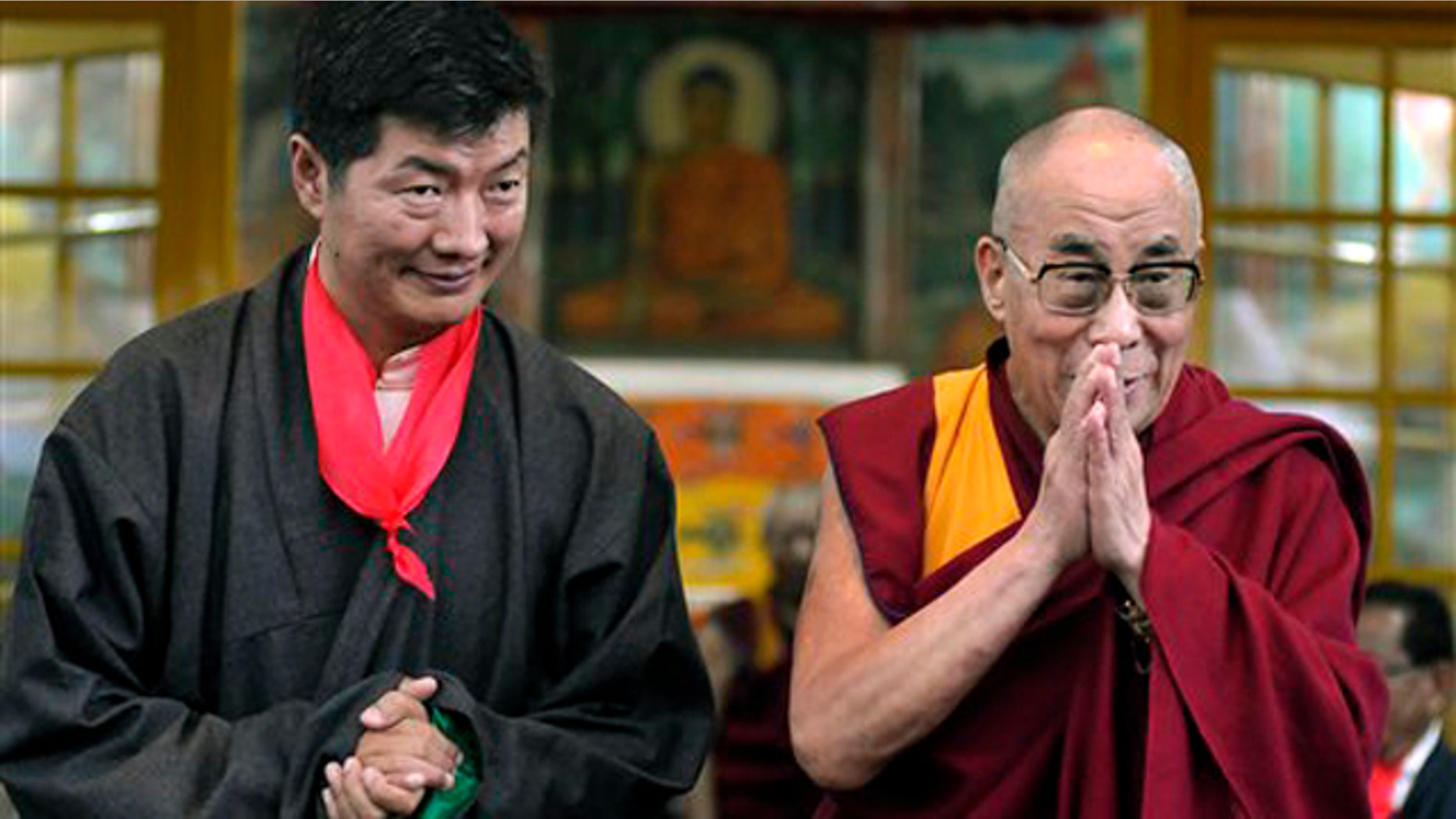 Lobsang Sangay, left, the new prime minister of Tibet's government in exile, stands next to Tibetan spiritual leader the Dalai Lama as he greets the crowd at his swearing-in ceremony at the Tsuglakhang Temple in Dharmsala, India, Monday, Aug. 8, 2011.