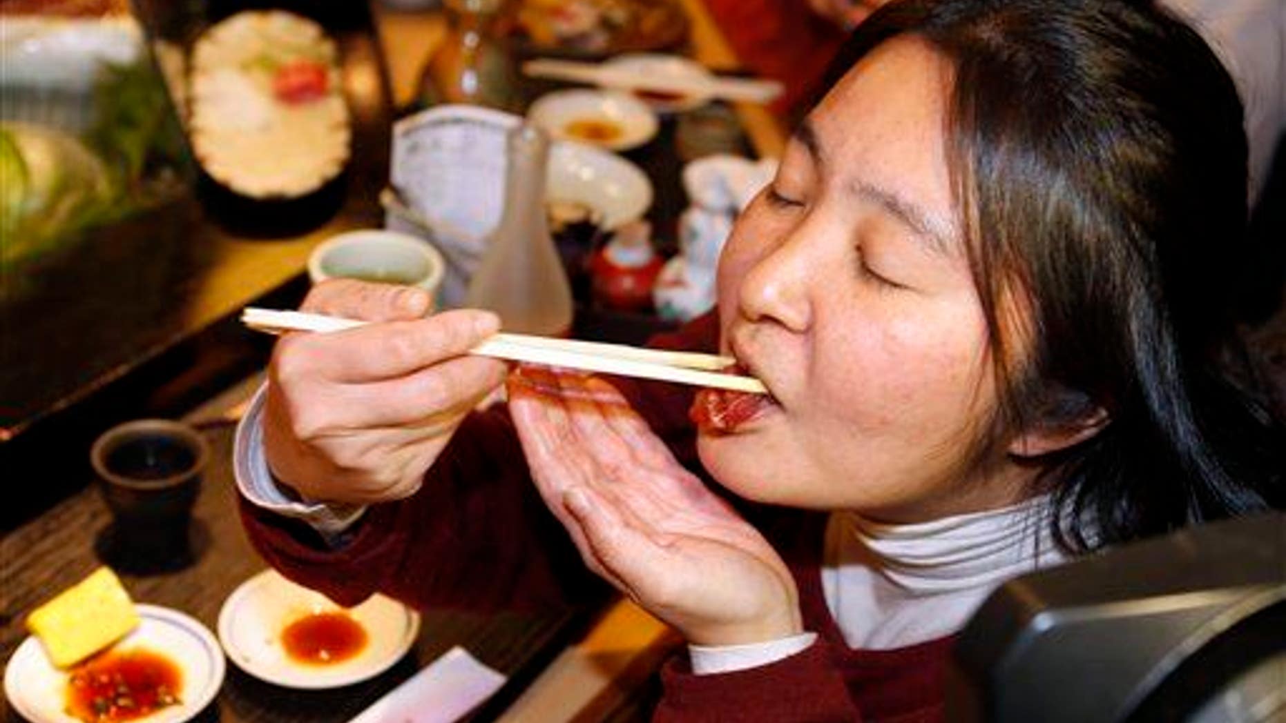 A woman eats a sushi of a bluefin tuna in Tokyo.
