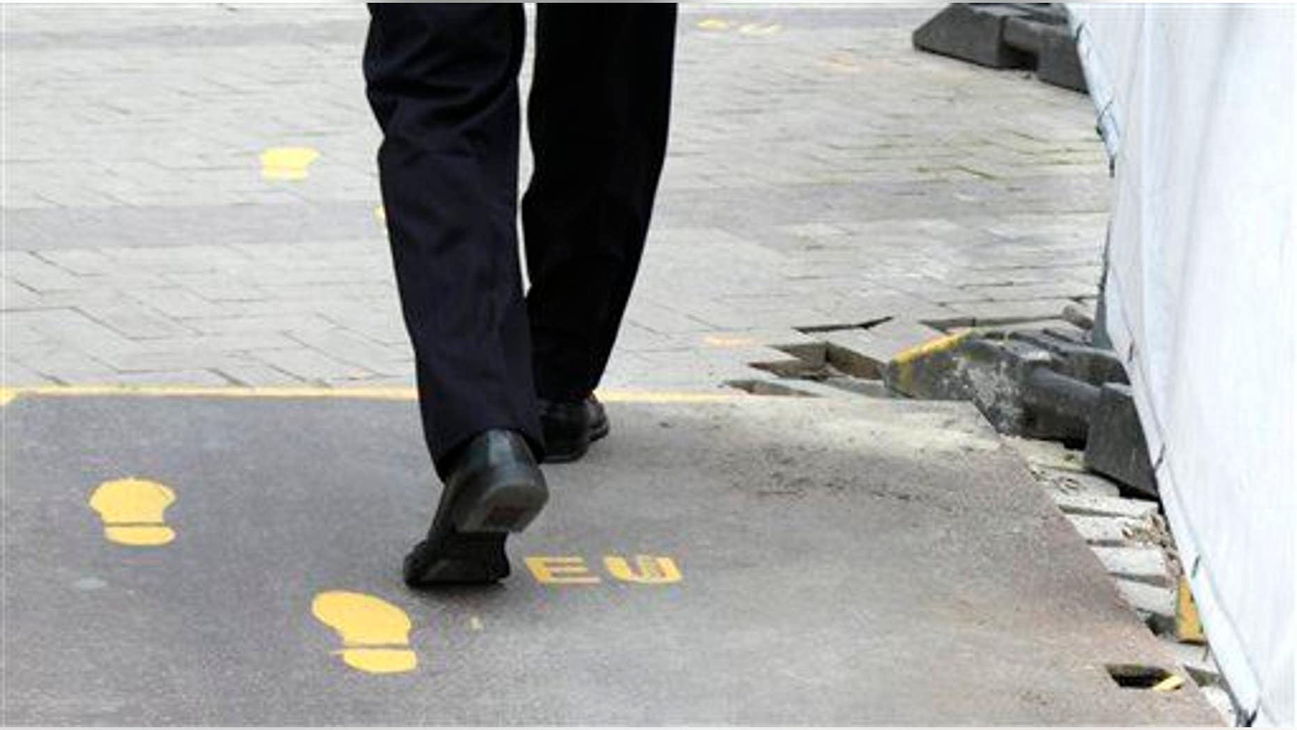 A man follows a yellow foot path in Brussels, Wednesday, June 27, 2012.