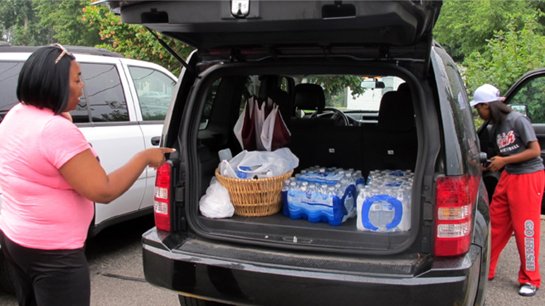 August 2, 2014: Aundrea Simmons stands next to her minivan with cases of bottled water she bought after Toledo warned residents not to use its water. About 400,000 people in and around Ohio's fourth-largest city were warned not to drink or use its water after tests revealed the presence of a toxin possibly from algae on Lake Erie. (AP Photo/John Seewer)