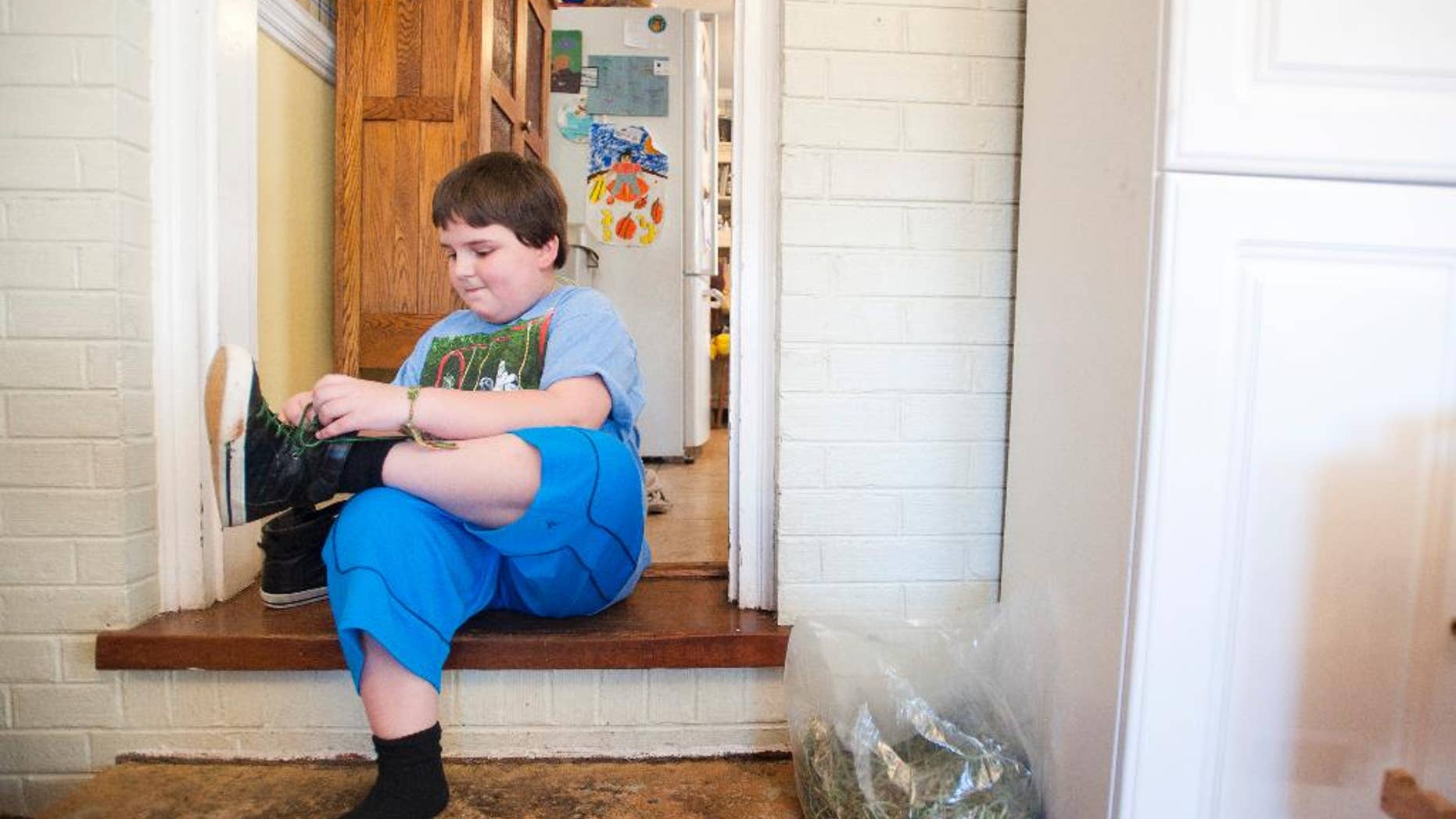 Sunnie Kahle, 8, puts on her shoes before leaving her home in Forest, Va. on March 26, 2014. Kahle recently withdrew from Timberlake Christian School in Forest, Va. after the school sent a letter asking her to either dress and act more feminine or not enroll again because she looked too much like a boy. (AP Photo/The News & Advance, Jill Nance)