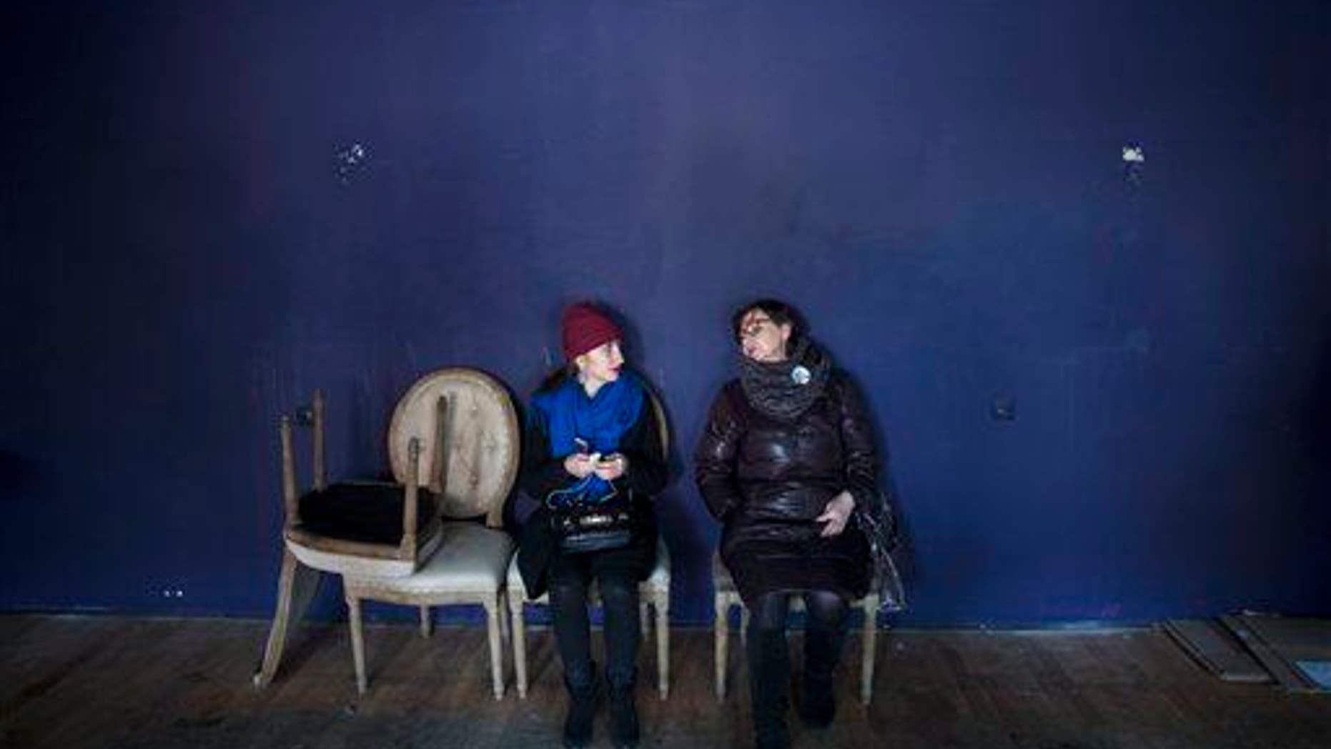 In this photo taken on Sunday Jan. 25, 2015, women sit on the chairs they bought from the closed restaurant in Moscow, Russia. Chairs, tables, designer chandeliers, and an enormous pink lamp in the shape of a bears head: at The Red Fox and the Lazy Hound, an upscale restaurant that is one of many closing in Moscow this month, everything must go. And surprisingly, Muscovites have come out in numbers to find cheap deals. Frugality is making a comeback _ with no end in sight to Western sanctions or the painful drop in Russias oil revenues, there is a creeping awareness that the tough times are here to stay. (AP Photo/Pavel Golovkin)