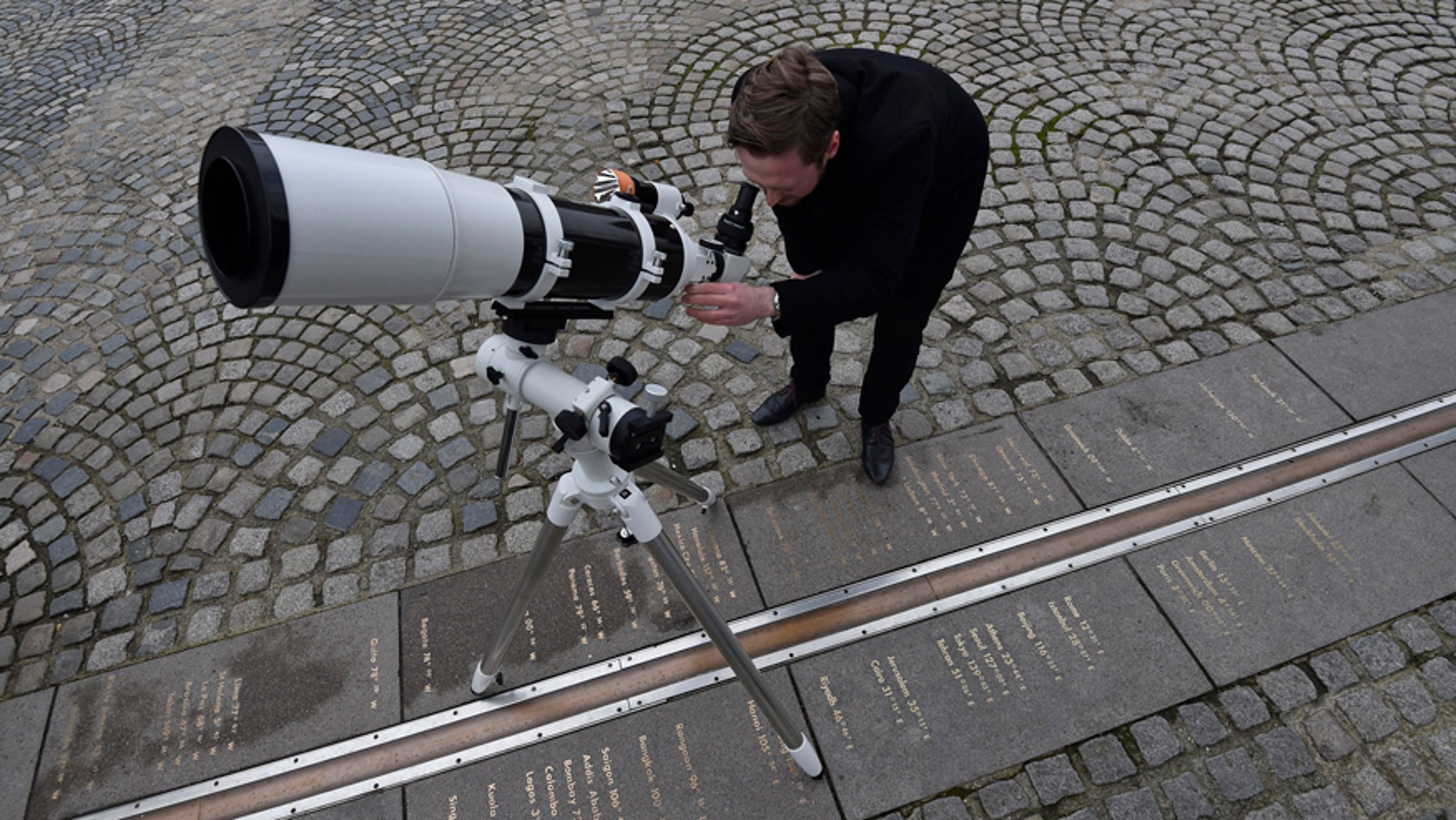 Astronomer Brendan Owens poses with a refractive telescope on the Meridian line at The Royal Observatory in Greenwich, south east London March 19, 2015.