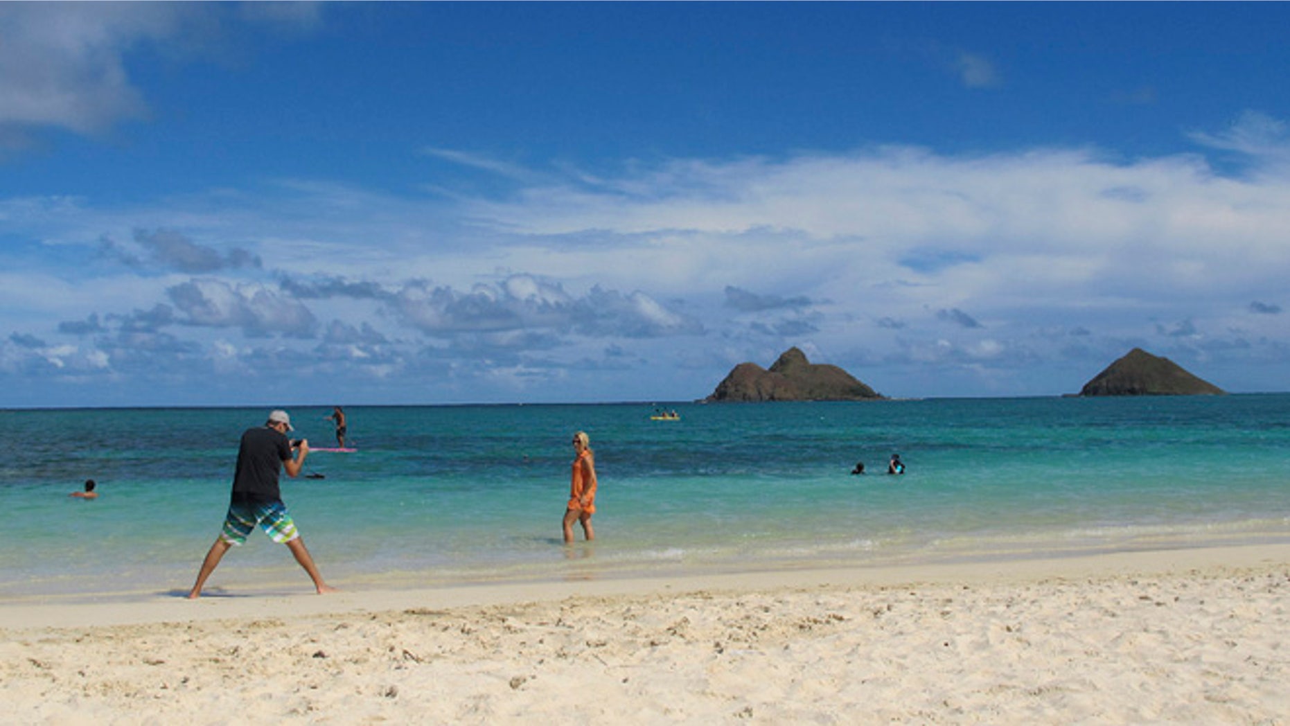 This Oct. 29, 2013 photo shows tourists on Lanikai Beach in Kailua, Hawaii. The Kailua Neighborhood Board is upset about a thriving industry of illegal bed-and-breakfast and vacation rentals and is asking the state tourism agency to stop encouraging visitors to stay overnight in their town.