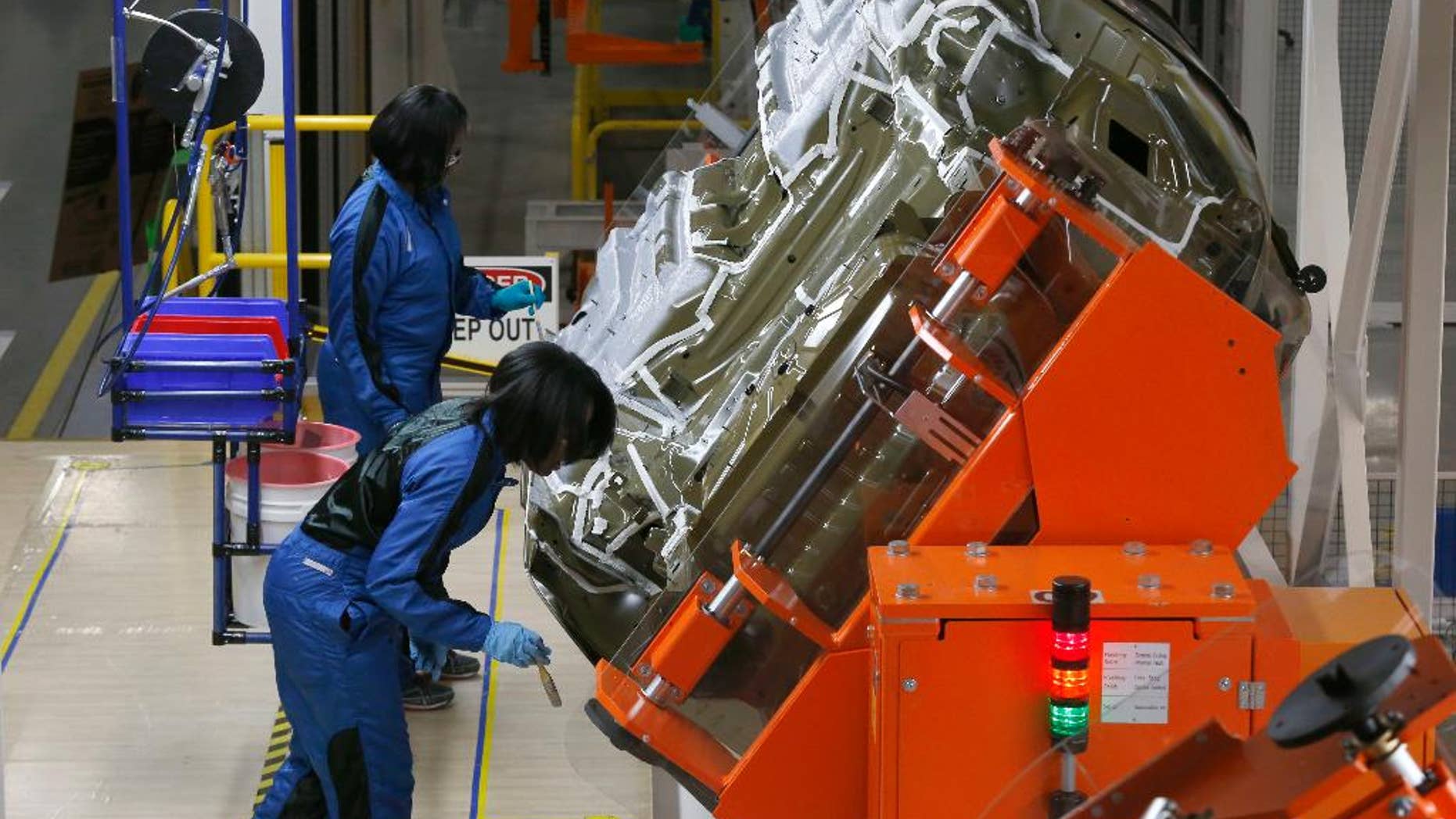 In this March 14, 2014 photo, assembly line workers build a 2015 Chrysler 200 automobile at the Sterling Heights Assembly Plant in Sterling Heights, Mich. The Commerce Department reports on the U.S. trade deficit for August on Friday, Oct. 3, 2014. (AP Photo/Paul Sancya)