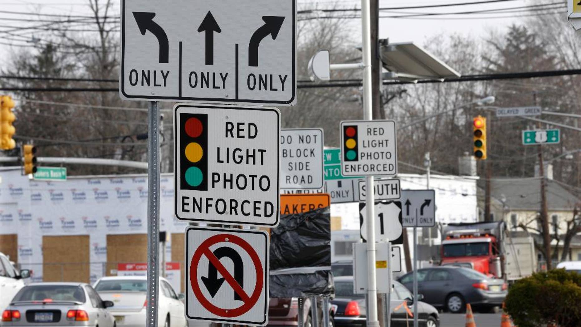 FILE - In a Tuesday, Dec. 16, 2014 file photo, traffic passes a red light photo enforcement sign below a red light camera at the intersection of Route 1 and Franklin Corner Road, in Lawrence Township, N.J. New Jersey legislators recently discontinued the state’s red light camera pilot program after five years. The number of red-light cameras nationwide is falling because of opposition from lawmakers and average Joes _ but the use of cameras to catch speeders is slowly rising, potentially signaling a new battleground. (AP Photo/Mel Evans, File)
