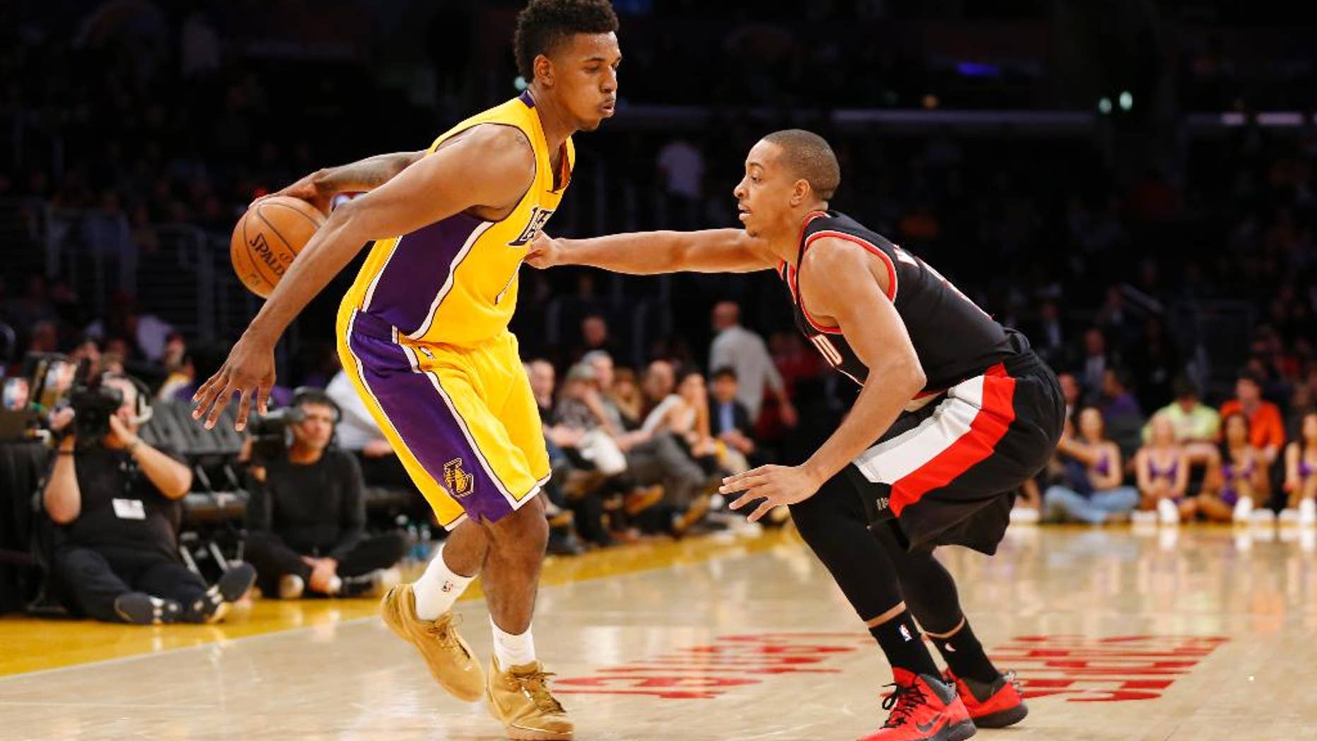 Los Angeles Lakers forward Nick Young dribbles behind his back as Portland Trail Blazers guard C.J. McCollum defends during the second half of an NBA basketball game in Los Angeles, Tuesday, April 1, 2014. The Trail Blazers won 124-112. (AP Photo/Danny Moloshok)