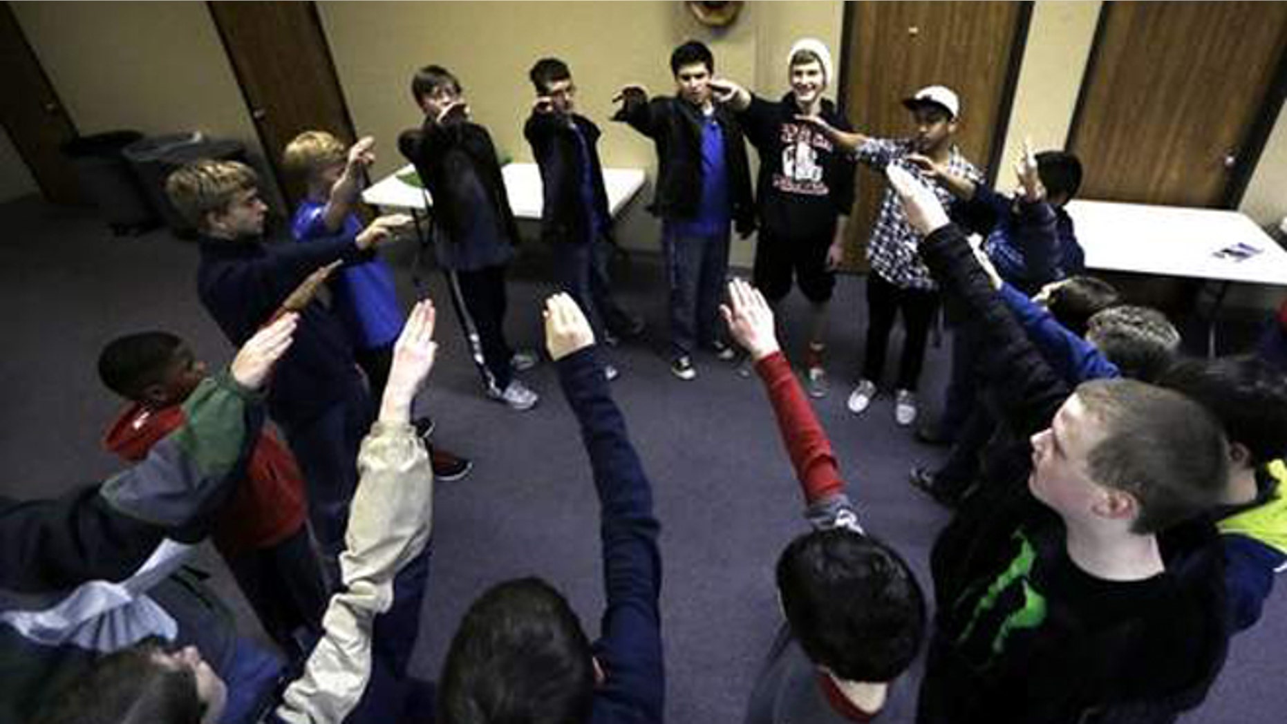 Trail Life members move their arms as they and sing "Taps" in a circle during a meeting in North Richland Hills, Texas. Trail Life USA, the new Christian-based alternative to the Boy Scouts of America, excludes openly gay members.