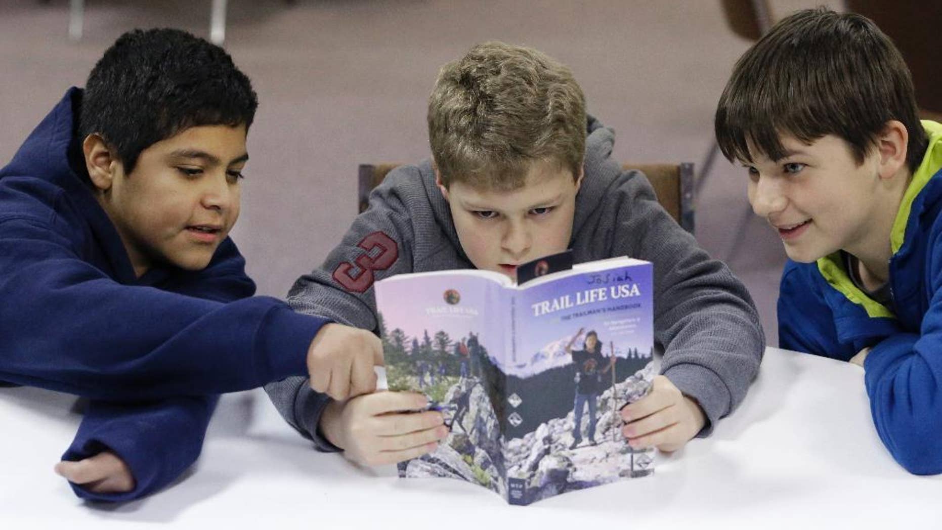 In this Tuesday, Feb. 4, 2014 photo, from left, Erick Izquierdo, Josiah Spear, 12, and Cole McSorley, 12, look at a Trail Life handbook during a gathering of members in North Richland Hills, Texas. Trail Life USA says it has established units in more than 40 states, mostly from Boy Scouts and parents who feel the century-old organization has lost its way. (AP Photo/LM Otero)