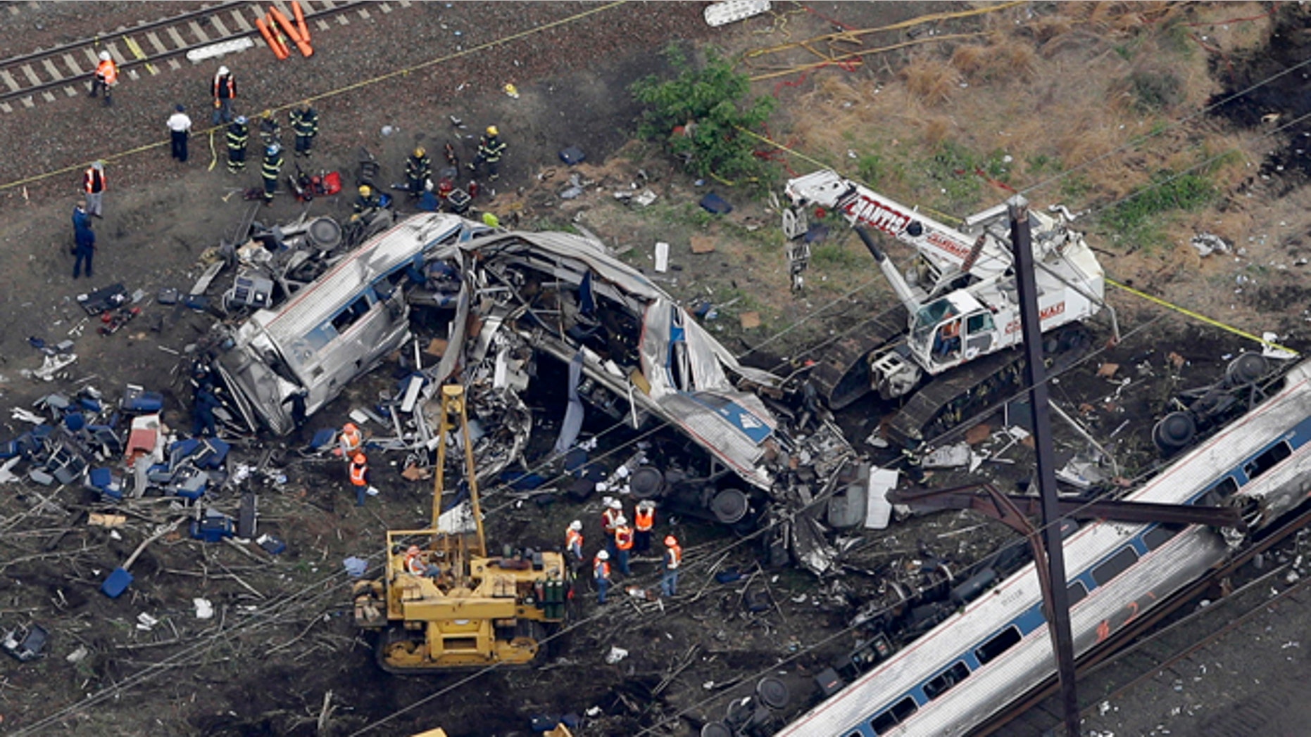 In this aerial photo taken May 13, 2015, emergency personnel work at the scene of a deadly train wreck in Philadelphia. Amtrak faces what probably will be a $200 million payout to crash victims _ the cap established by Congress nearly 20 years ago as part of a compromise to rescue the railroad from financial ruin. It would be the first time that the liability ceiling, considered by many to be too low to cover the costs of the eight lives lost and 200 people injured, designed for Amtrak actually would apply to the railroad. (AP Photo/Patrick Semansky)