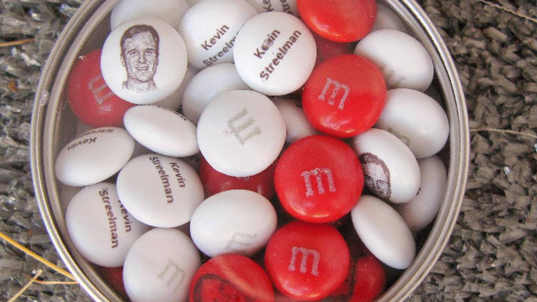 This personalized tin of M&M candies printed with the face and name of 2014 Travelers Golf Championship winner Kevin Streelman is seen Wednesday, June 24, 2015 in Cromwell, Conn. The tournament, which begins Thursday, has become known for the little perks it offers golfers, including giving the champion a supply of personalized M&Ms. (AP Photo/Pat Eaton-Robb)