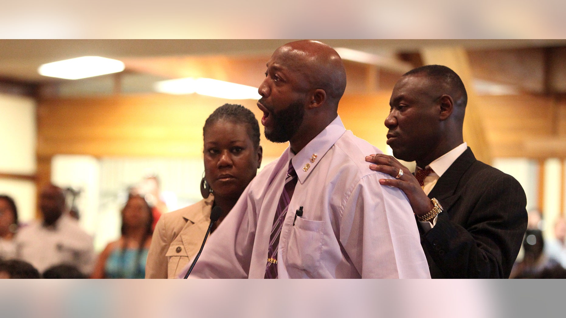 Tracy Martin, center, speaks at the Sanford City Commission meeting with Trayvon's mother, Sybrina Fulton, left, and the family lawyer, Benjamin Crump at the Sanford Civic Center in Sanford Fla., Monday, March 26, 2012. Martin, a black teen, was fatally shot by a neighborhood watch captain last month. (AP Photo/Julie Fletcher)