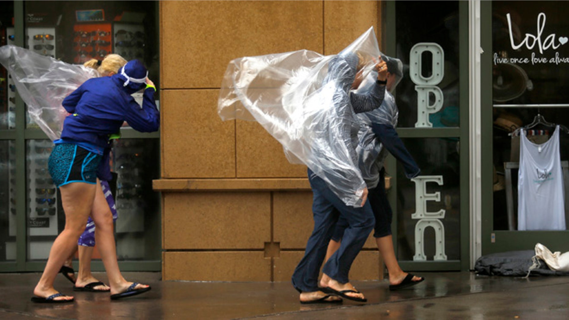 Pedestrians brave the wind rushing down Atlantic Ave. in Virginia Beach, Va., on Saturday, Sept. 3, 2016, as Tropical Storm Hermine approaches the region. The National Hurricane Center says Tropical Storm Hermine could bring 4 to 7 inches of rain to southeastern Virginia and the Atlantic coastal portion of Maryland as well as 1 to 4 inches of rain over southern Delaware, southern and eastern New Jersey and Long Island through Monday morning. (Stephen M. Katz/The Virginian-Pilot via AP)
