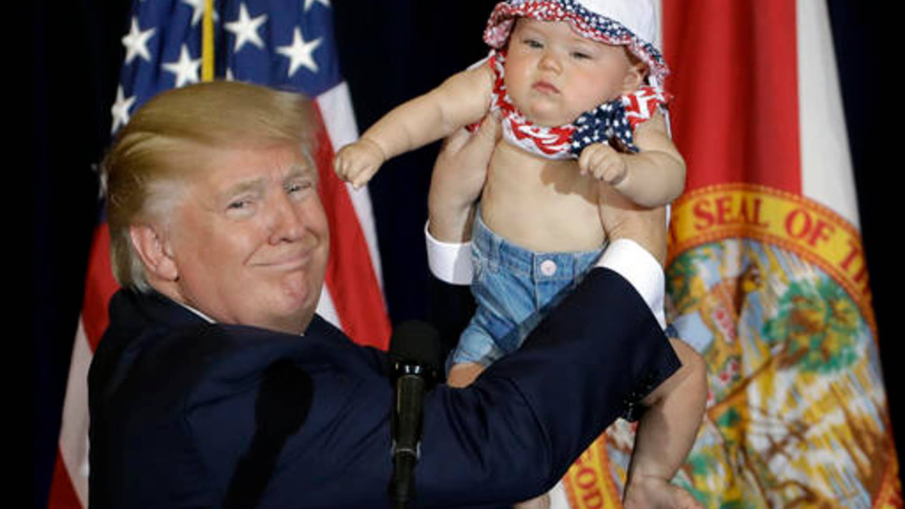Republican presidential candidate Donald Trump holds up 6-month-old Catalina Larkin, of Largo, Fla., during a campaign rally Saturday, Nov. 5, 2016, in Tampa, Fla. (AP Photo/Chris O'Meara)