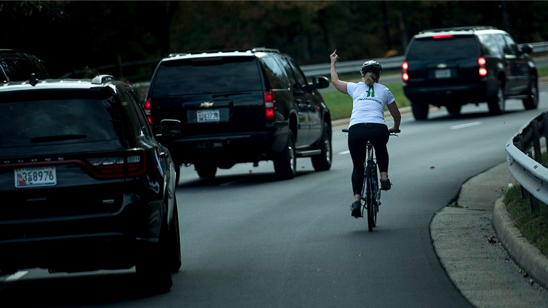 Juli Briskman gestures with her middle finger as a motorcade with US President Donald Trump departs Trump National Golf Course October 28, 2017 in Sterling, Virginia.