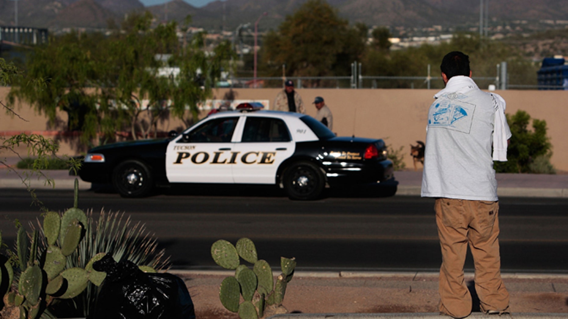 A Hispanic day laborer looking for work watches a police car parked across the street April 5, 2008 in Tucson, Arizona. (Photo by Chris Hondros/Getty Images)
