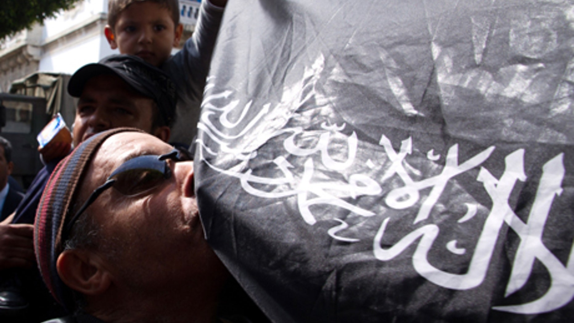 April 19, 2012: A Salafi Muslim kisses a flag reading "Only one god and Mohammed is his Prophet" ; outside the courthouse in Tunis for the trial of the Tunisian TV station for airing the prize-winning animated feature "Persepolis"; and allegedly insulted Islam.