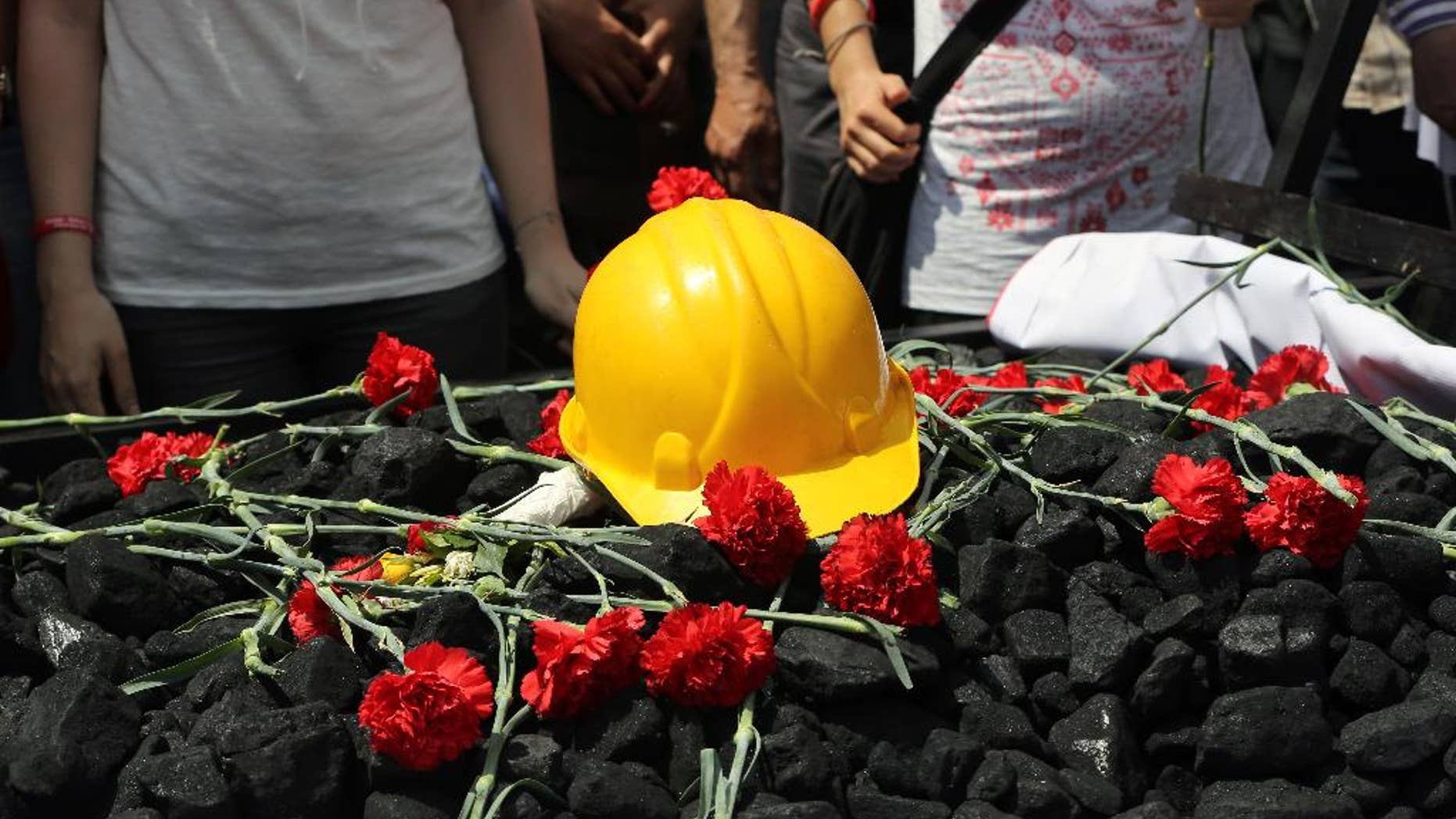 People place flowers on some coal and a hard hat as nearly 2,000 university students called on the government to resign as they marched to commemorate the beginning of the Turkish War of Independence started on May 19, 1919, in Ankara, Turkey, Monday, May 19, 2014. Government officials have promised to investigate and pledged that any mine officials found to be negligent would be punished. Still the disaster has provoked anger at a critical time for Prime Minister Recep Tayyip Erdogan, as he mulls running in August's presidential election. (AP Photo/Burhan Ozbilici)