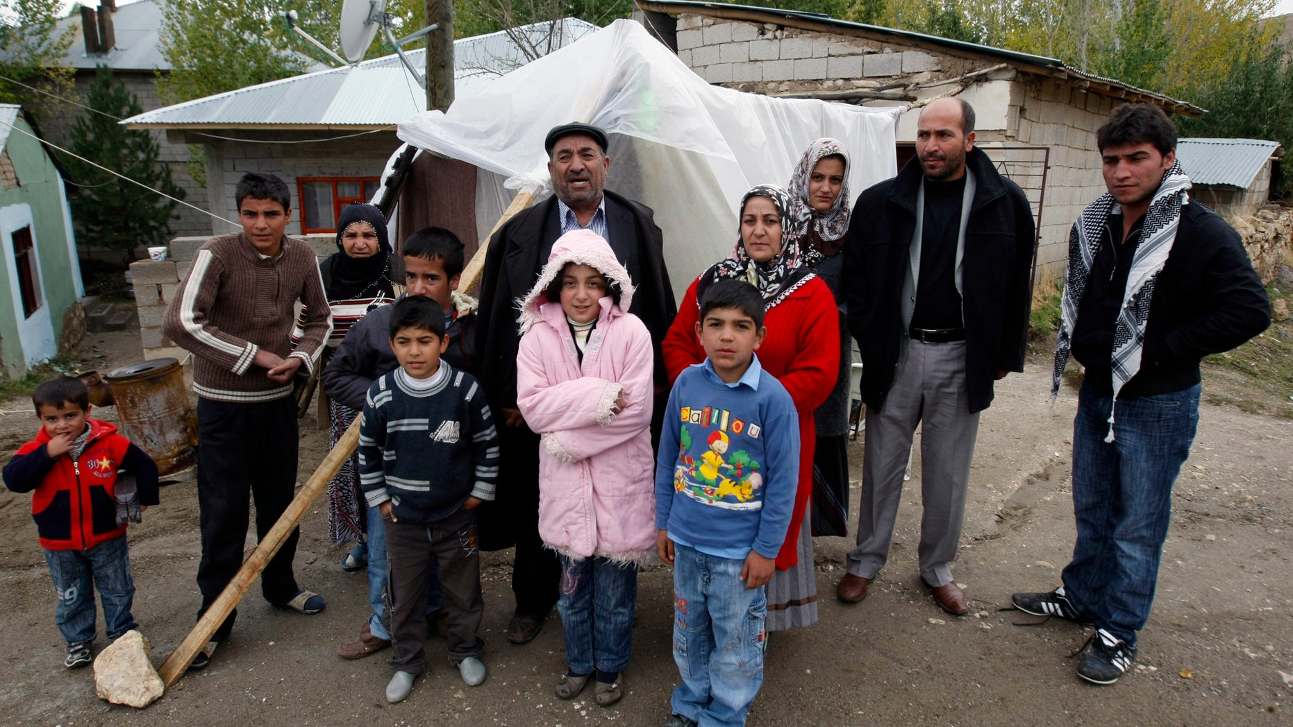 Oct. 27, 2011: Earthquake survivor, Adil Aktas, rear center, 56, and his family members stand outside their makeshift tent where about 10 people spent the night without any heating in a tent city set up in a soccer field in Ercis, Van, Turkey.