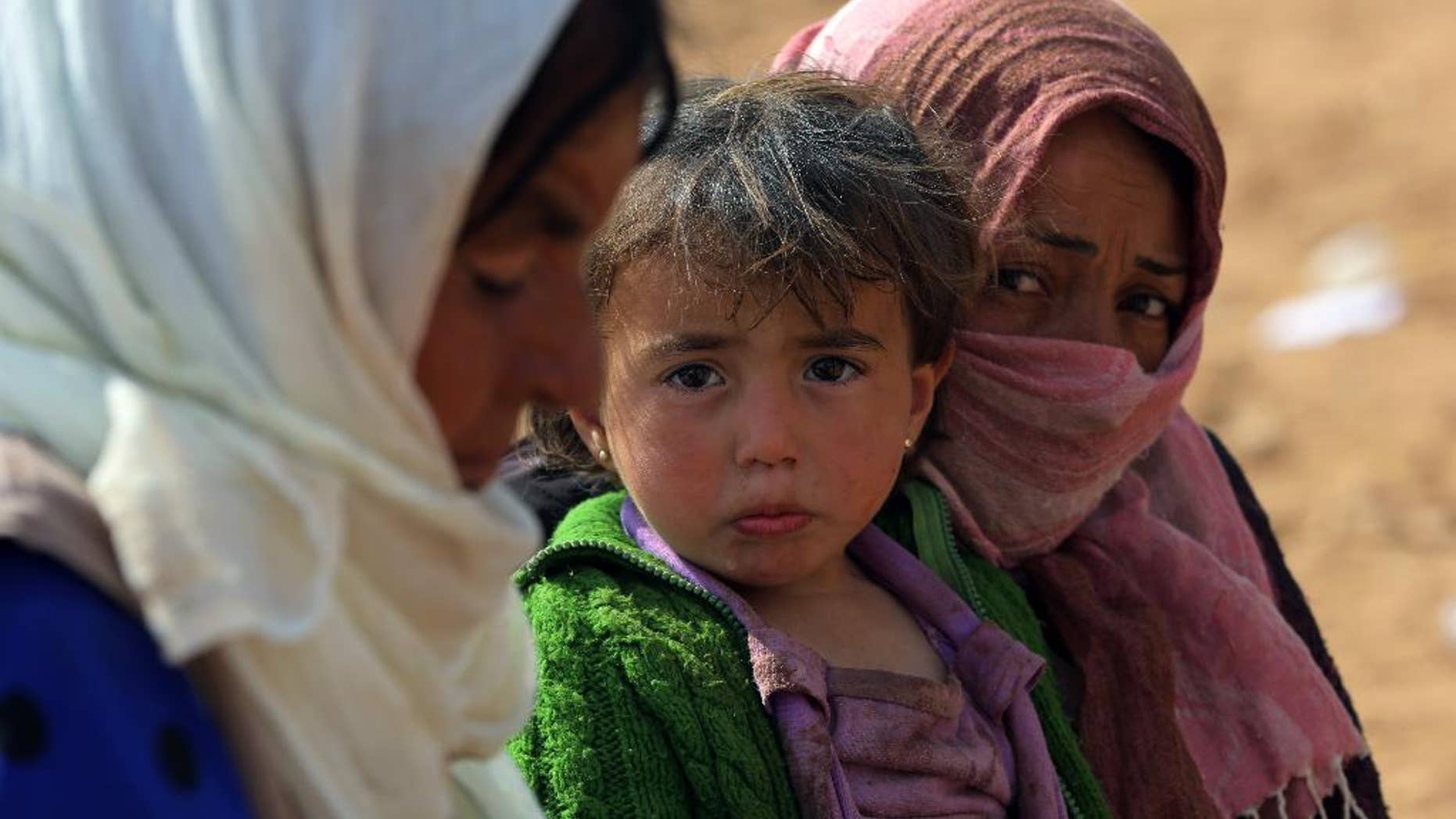 Syrian refugees, mostly Kurds from Kobani, rest after arriving at the Turkey-Syria border near Suruc, Turkey, Saturday, Sept. 27, 2014. (AP Photo/Burhan Ozbilici)