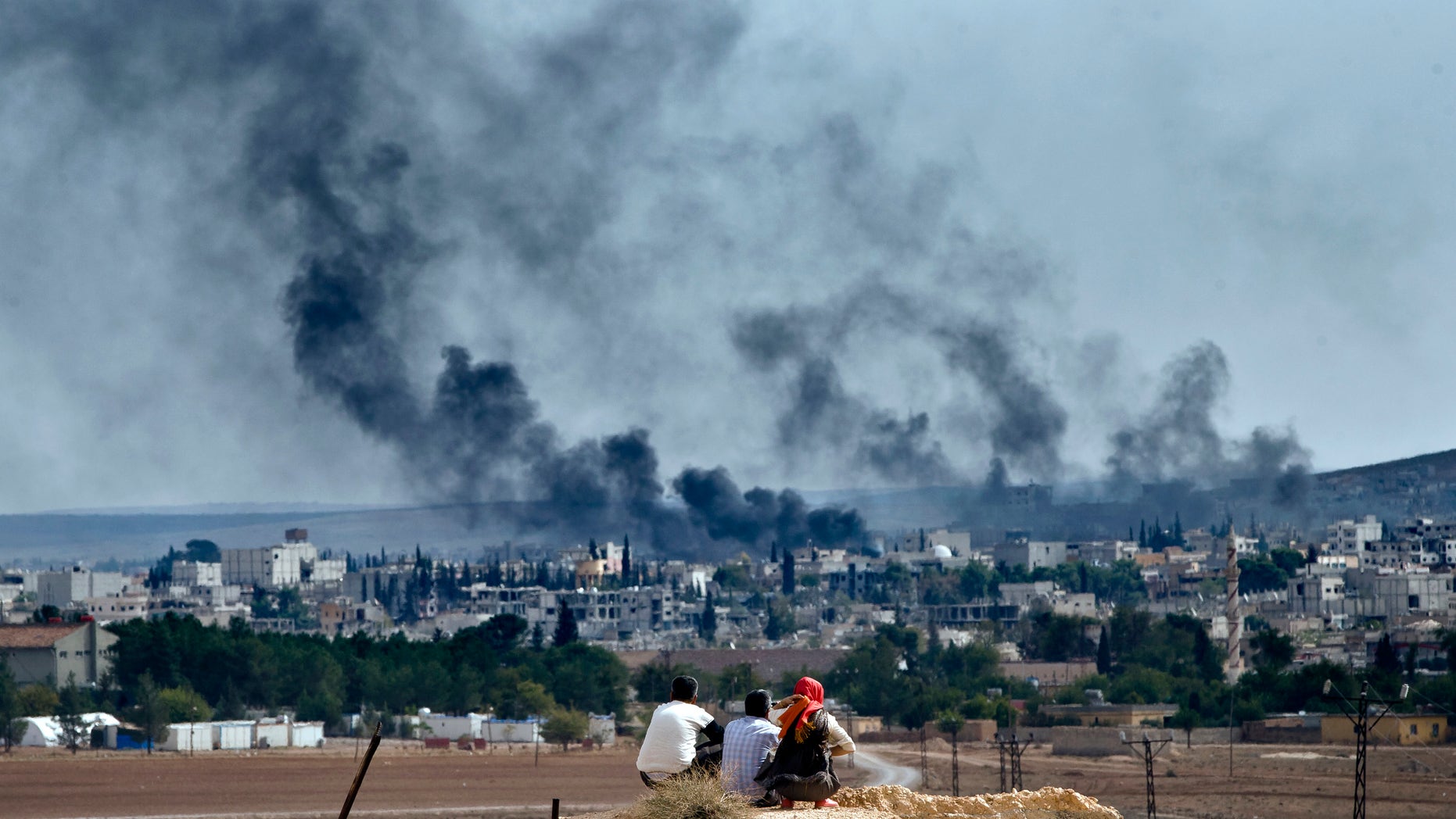 Oct. 26, 2014 - Syrian Kurdish refugees from Kobani watch fighting across the border in Kobani from the outskirts of Suruc, Turkey, near the Turkey-Syria border. A new UN report says the world is facing a challenge of foreign fighters in terror groups on an "unprecedented scale," with about 15,000 in Syria and Iraq alone.