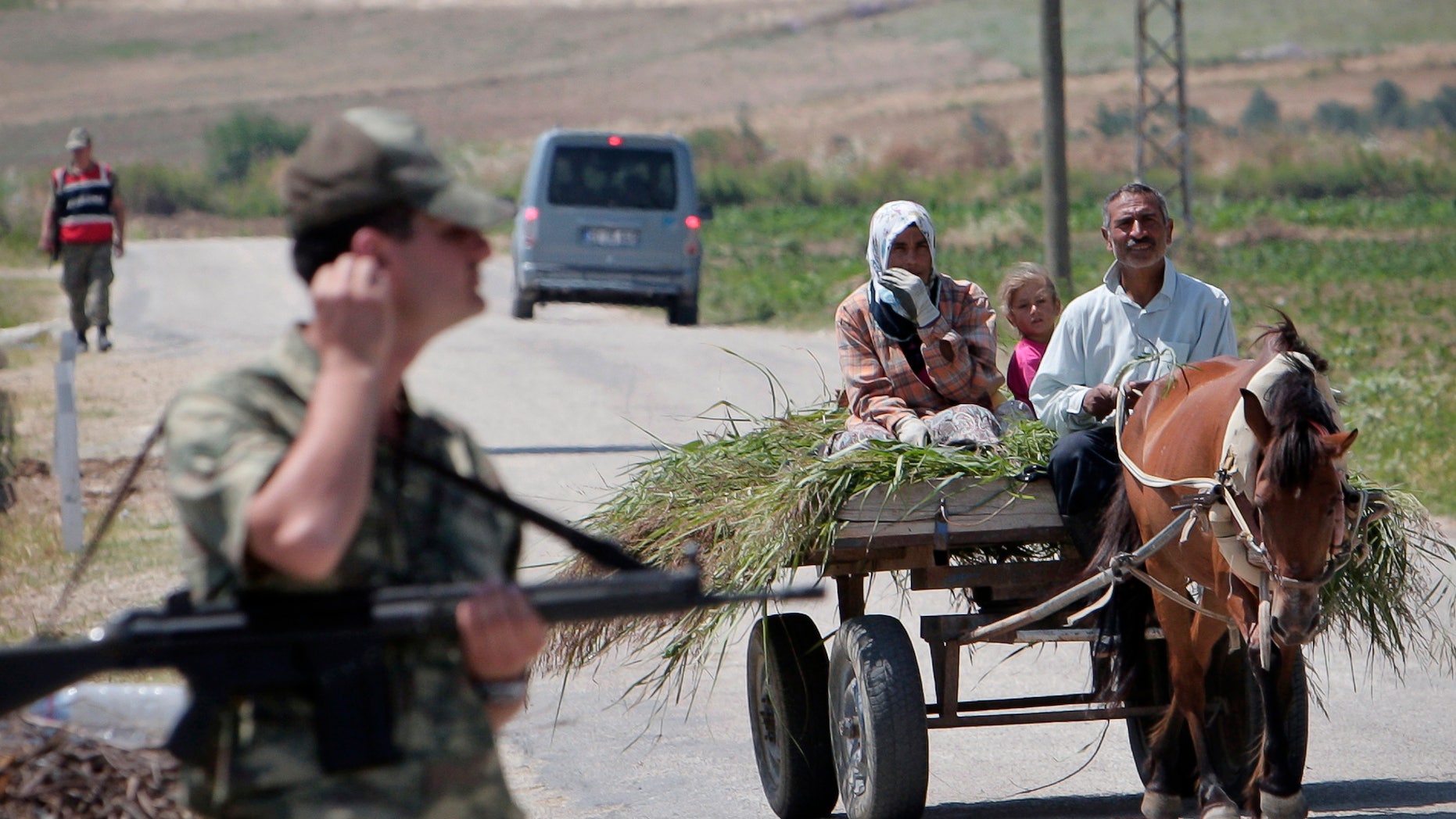 A Turkish family rides on a cart near Turkish soldiers guarding a Syrian refugee a camp, during a brief visit organized by Turkish authorities for the media, in Boynuyogun, Turkey, Saturday, June 18, 2011. According to Turkish authorities more than 10,000 Syrians are now in refugee camps in the Hatay province, near Turkey's border with Syria.